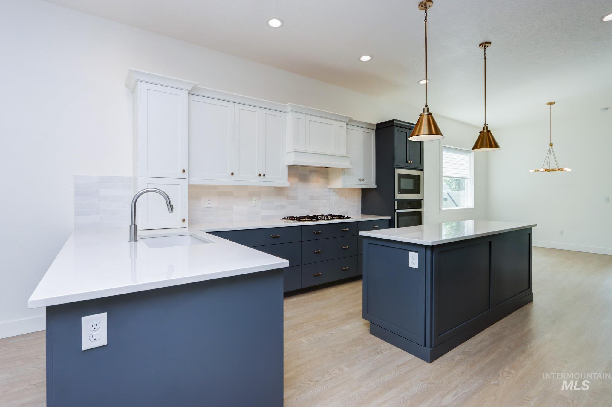 Kitchen featuring tasteful backsplash, light wood-style floors, white cabinetry, light countertops, and recessed lighting