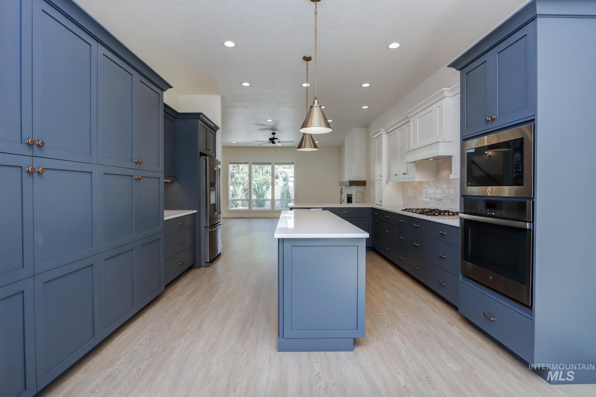 Kitchen with stainless steel appliances, a kitchen island, light countertops, decorative backsplash, and a peninsula