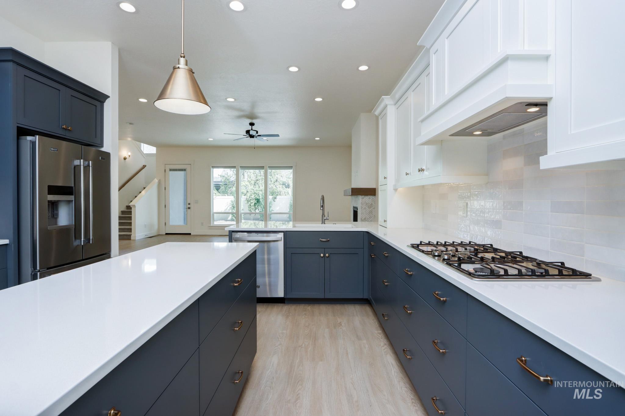 Kitchen with stainless steel appliances, light wood-style floors, light countertops, decorative backsplash, and recessed lighting