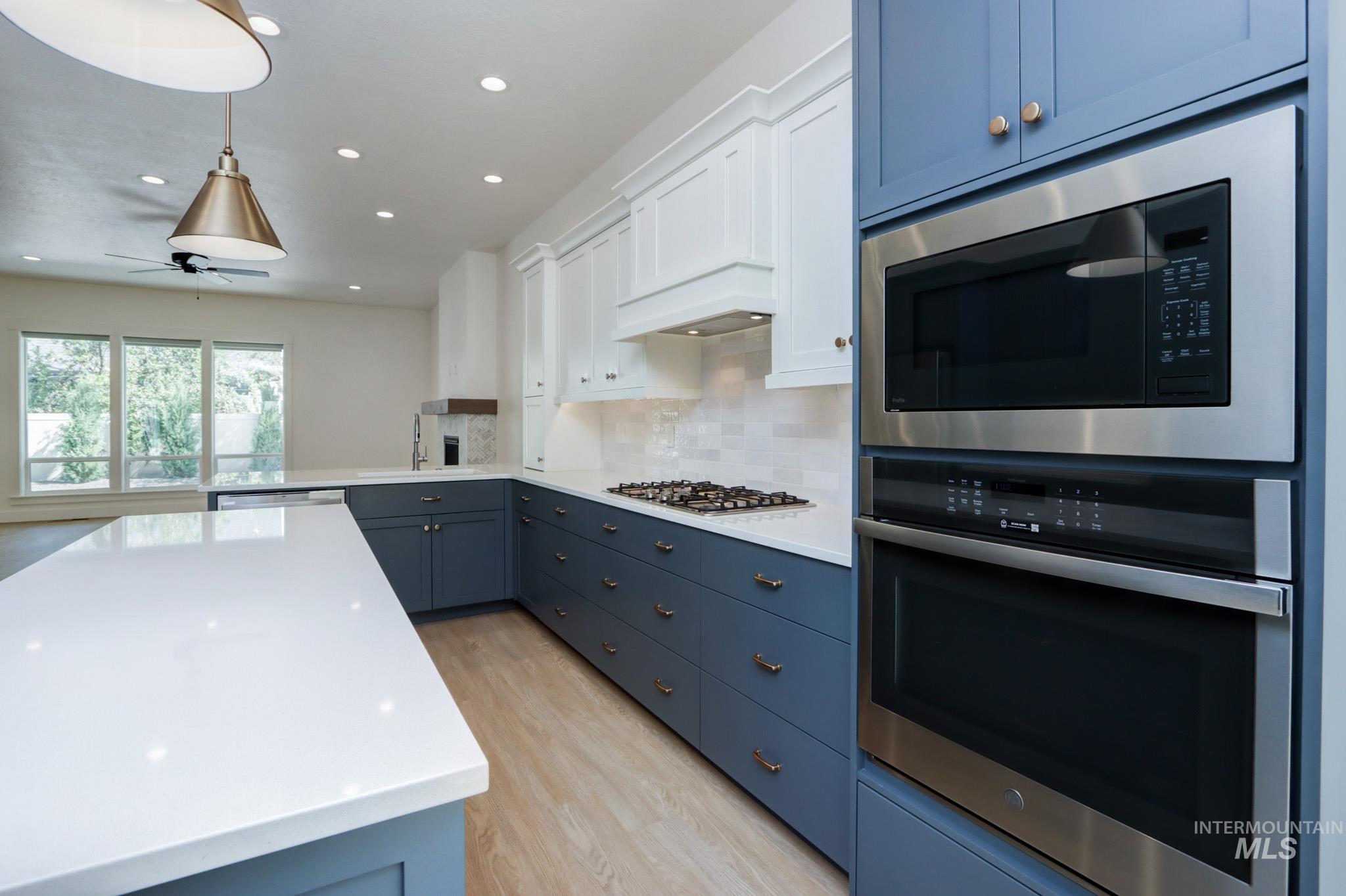 Kitchen featuring stainless steel appliances, blue cabinetry, recessed lighting, light wood-style floors, and light countertops