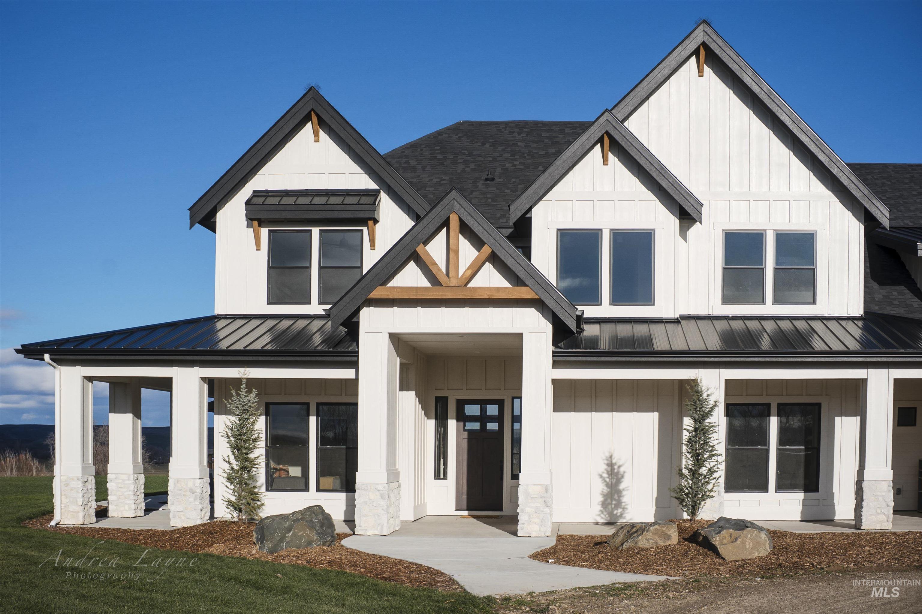 Modern farmhouse featuring a metal roof, a standing seam roof, board and batten siding, a porch, and stone siding