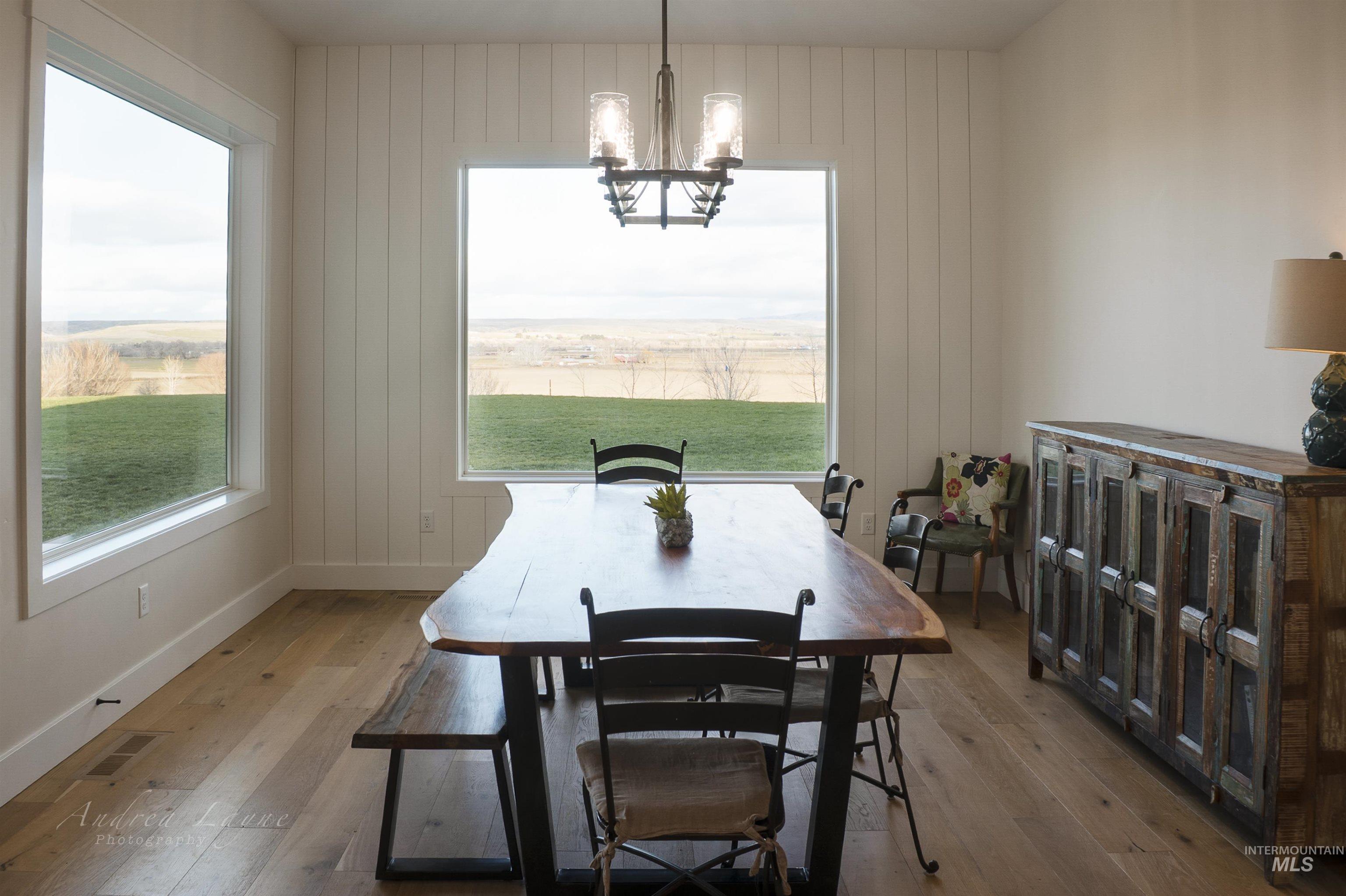 Dining space with wood-type flooring, a chandelier, and wooden walls