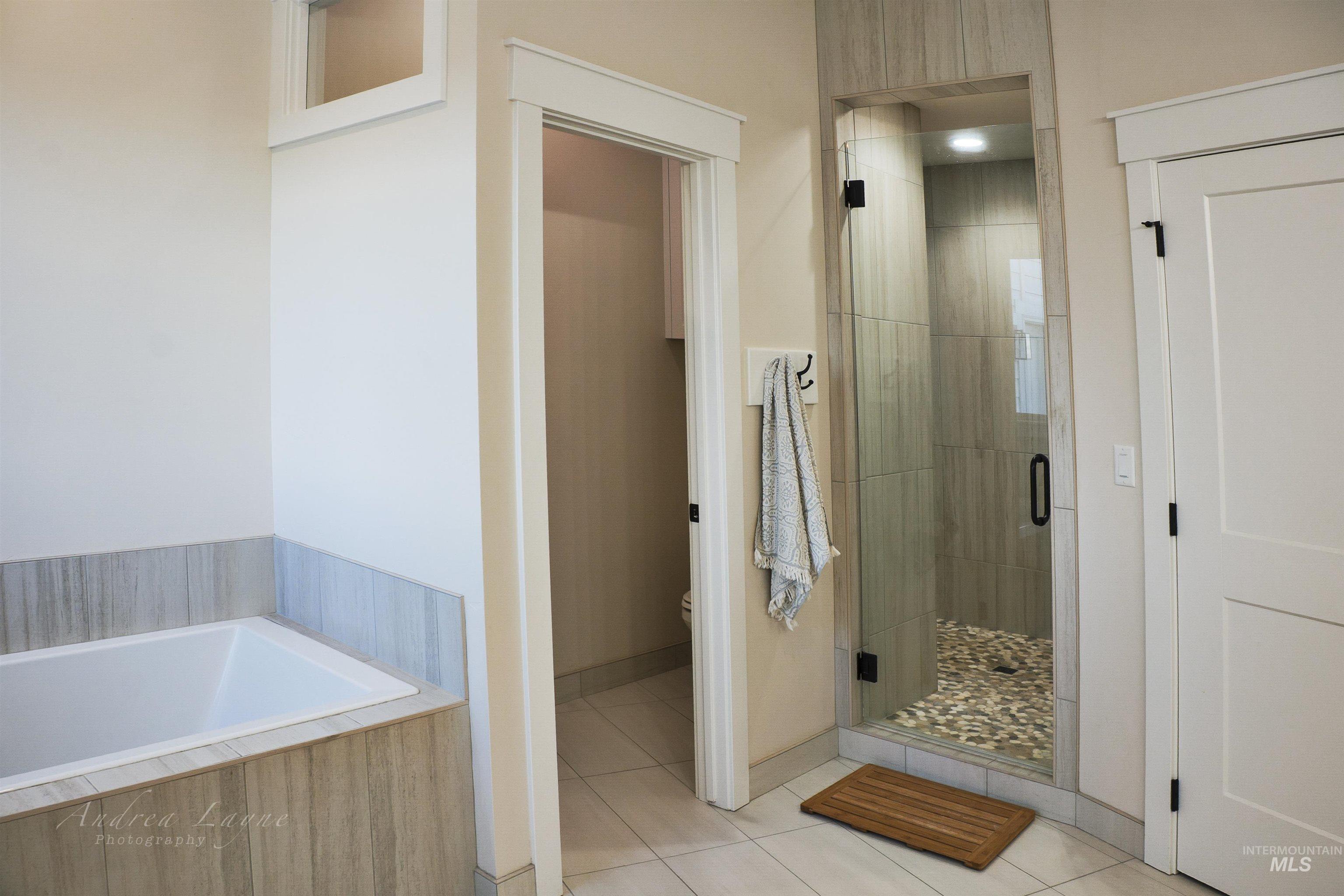 Bathroom featuring a shower stall, a garden tub, and light tile patterned flooring