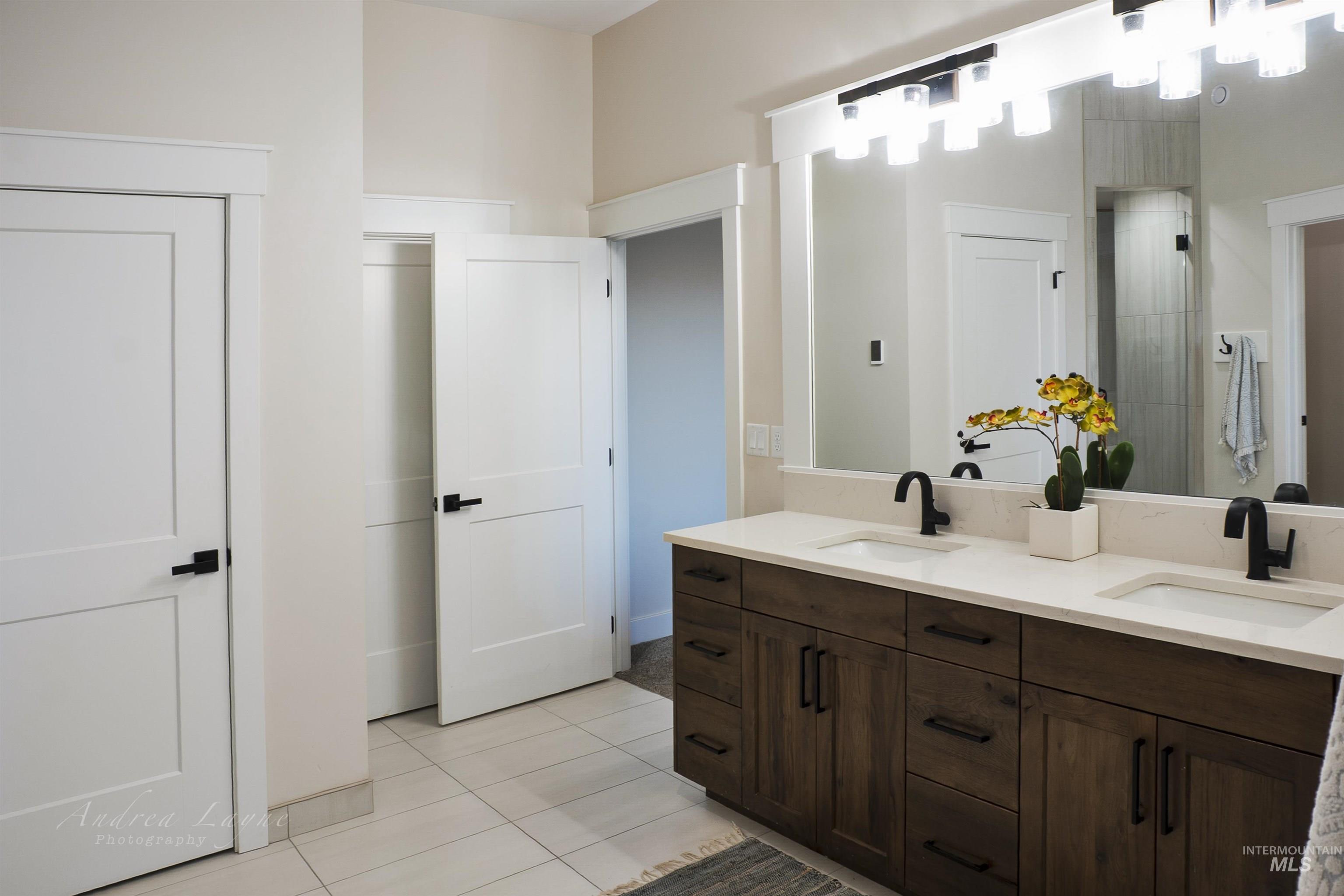 Full bathroom featuring double vanity, light tile patterned floors, and a shower stall