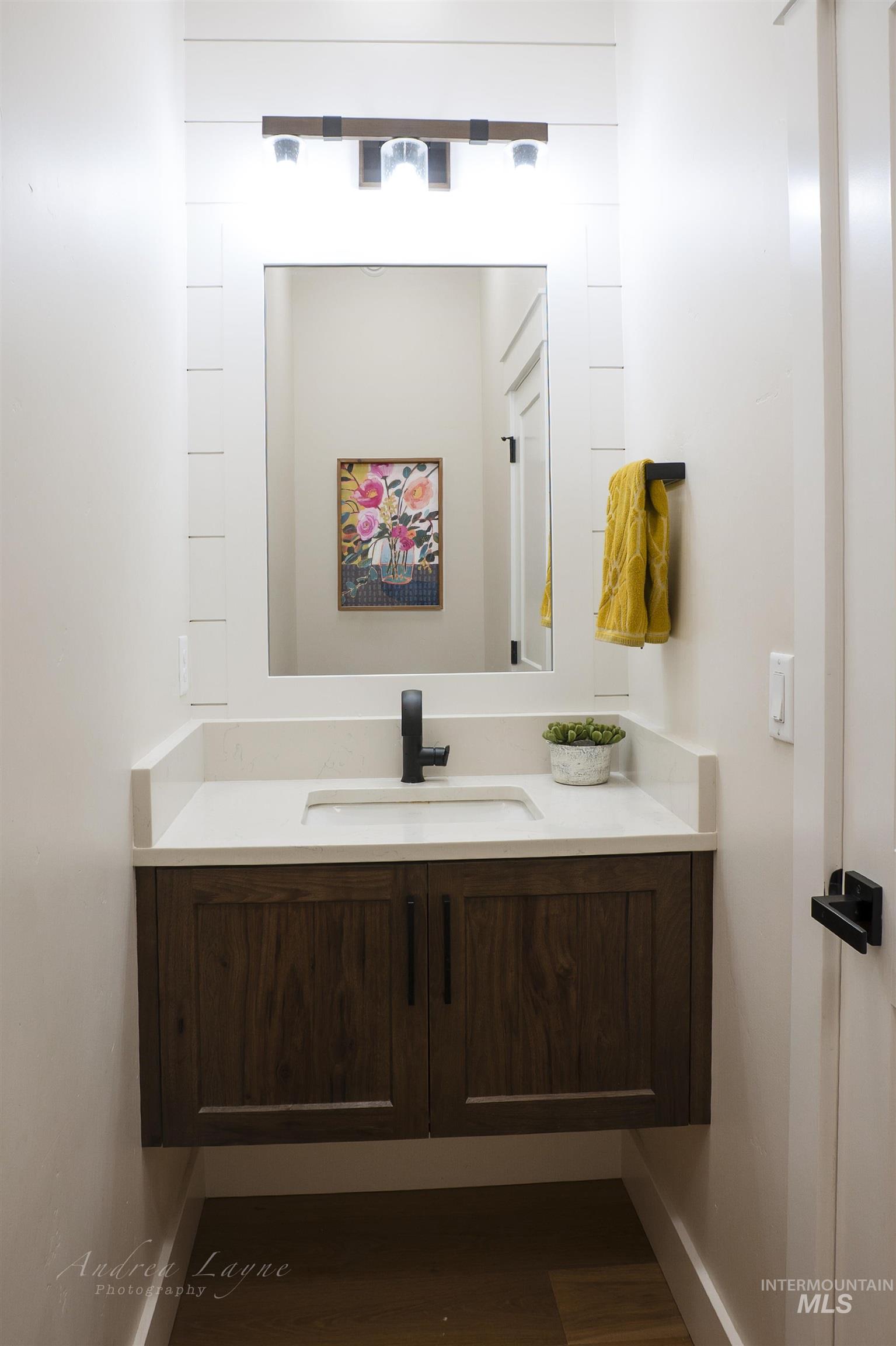 Half bath featuring vanity and dark wood-type flooring