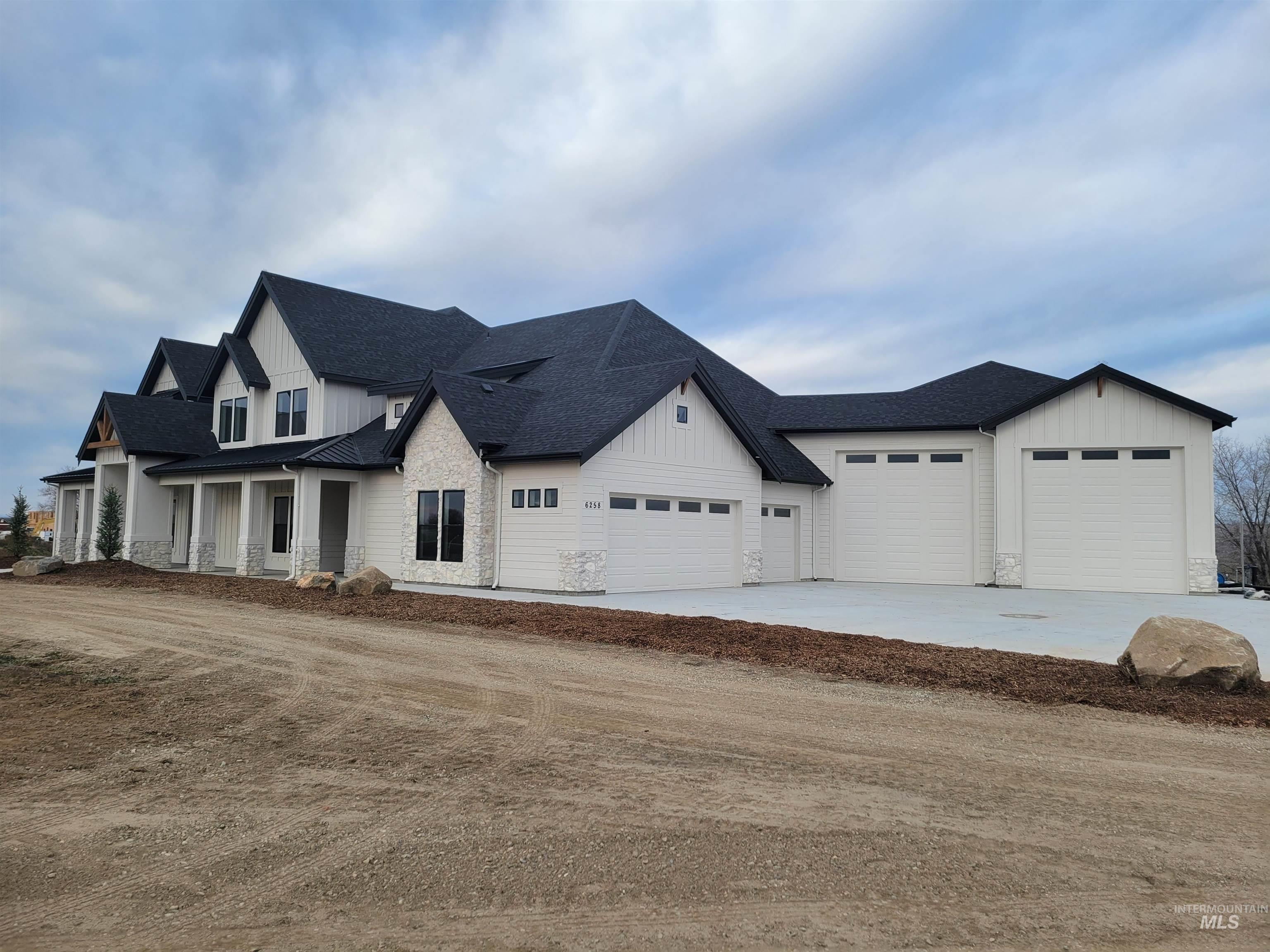 Modern farmhouse featuring a shingled roof, board and batten siding, and concrete driveway