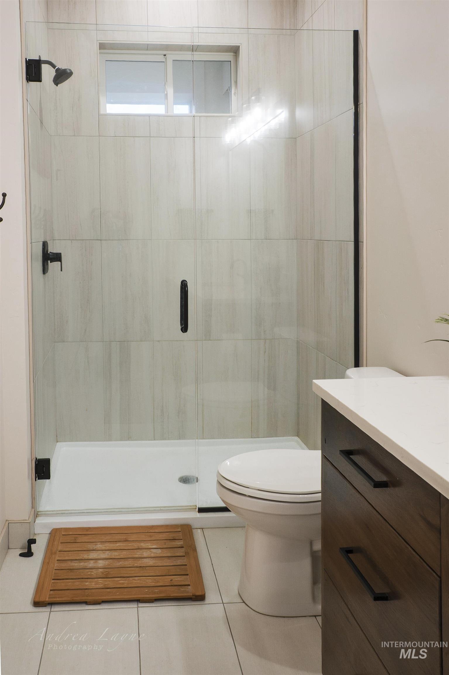 Full bath with vanity, a shower stall, and tile patterned floors