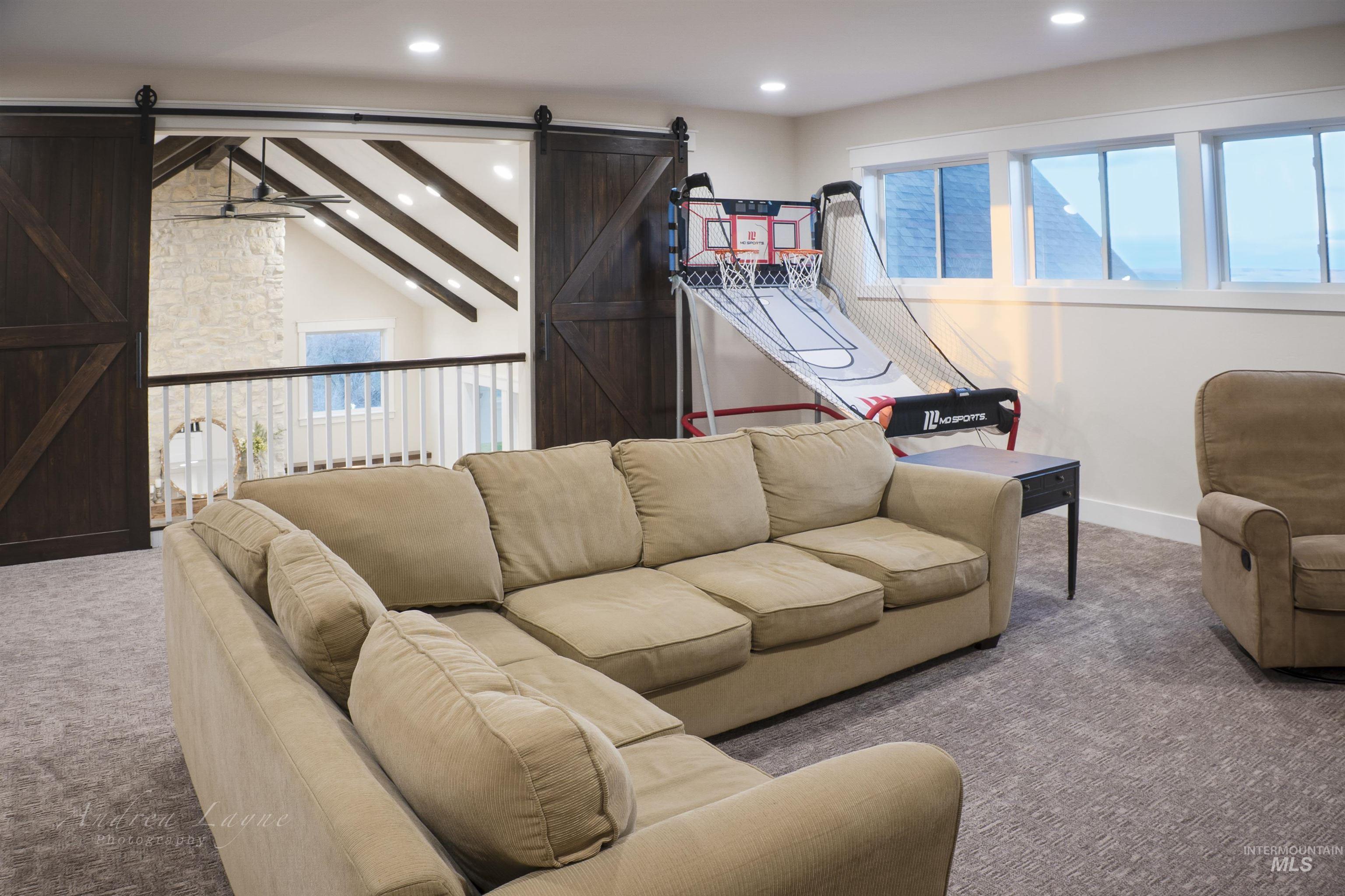 Living area with a barn door, carpet, plenty of natural light, beamed ceiling, and recessed lighting