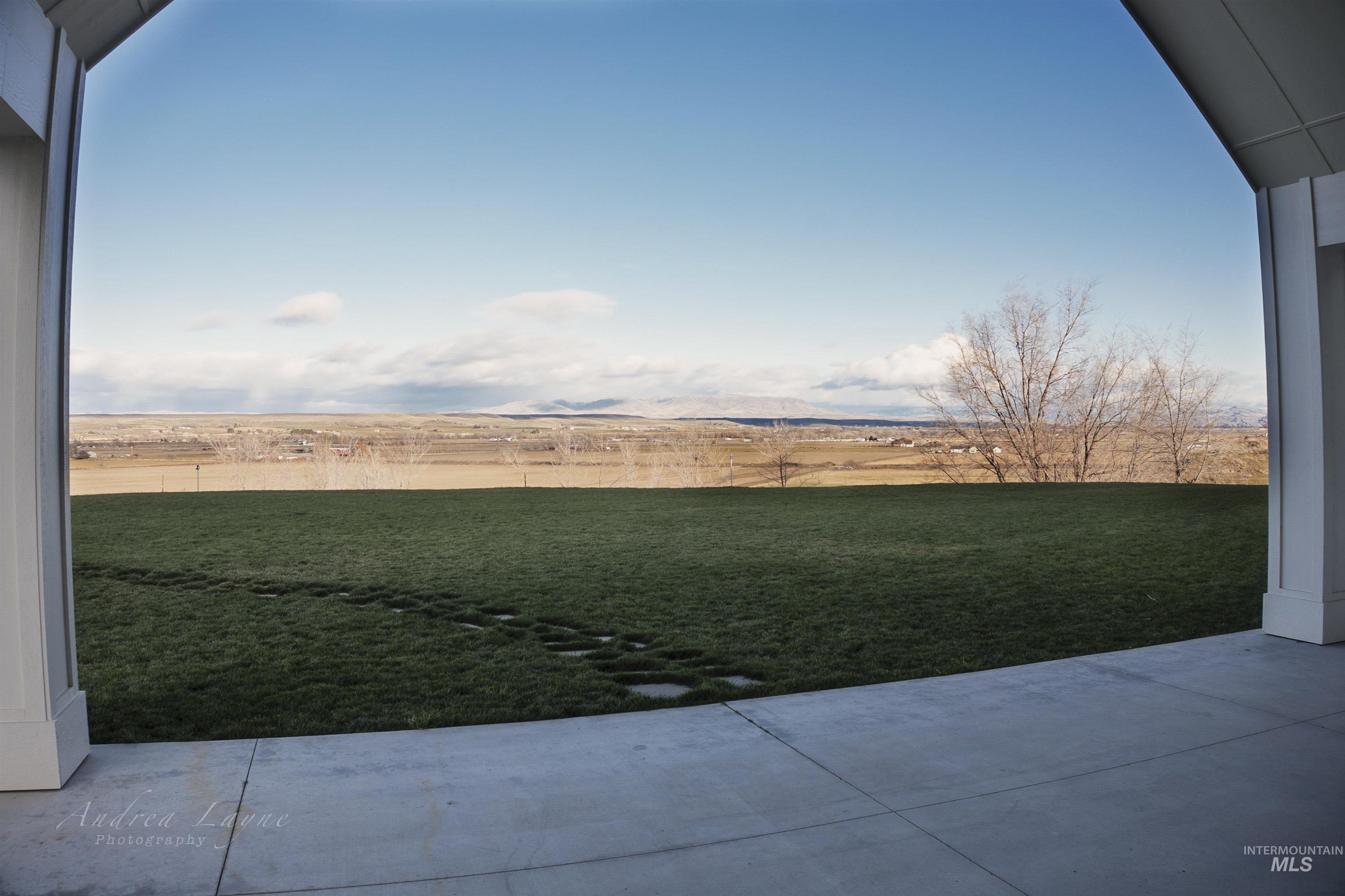 View of grassy yard with a patio and a view of rural / pastoral area
