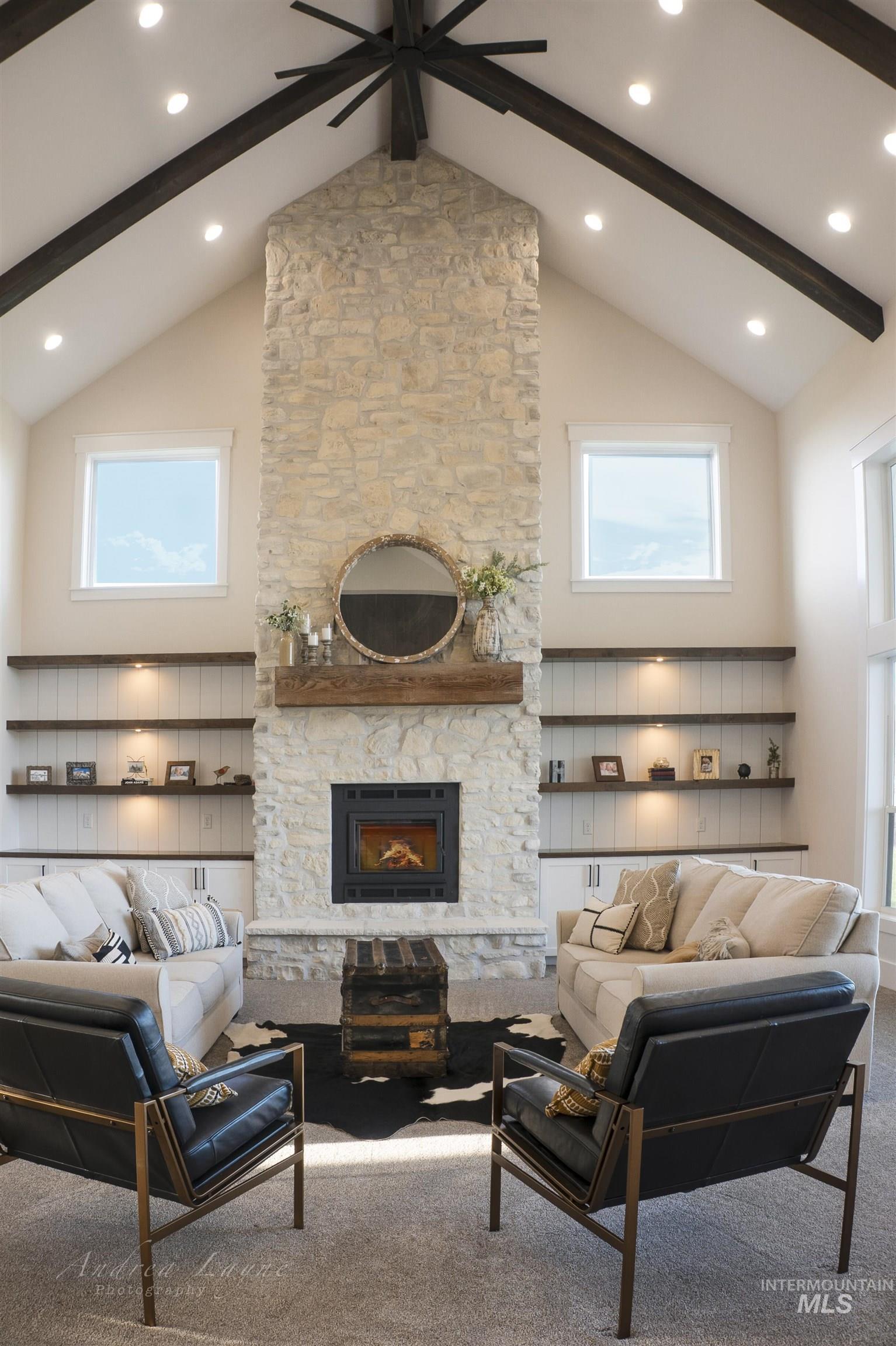 Carpeted living area with high vaulted ceiling, a fireplace, beam ceiling, and ceiling fan