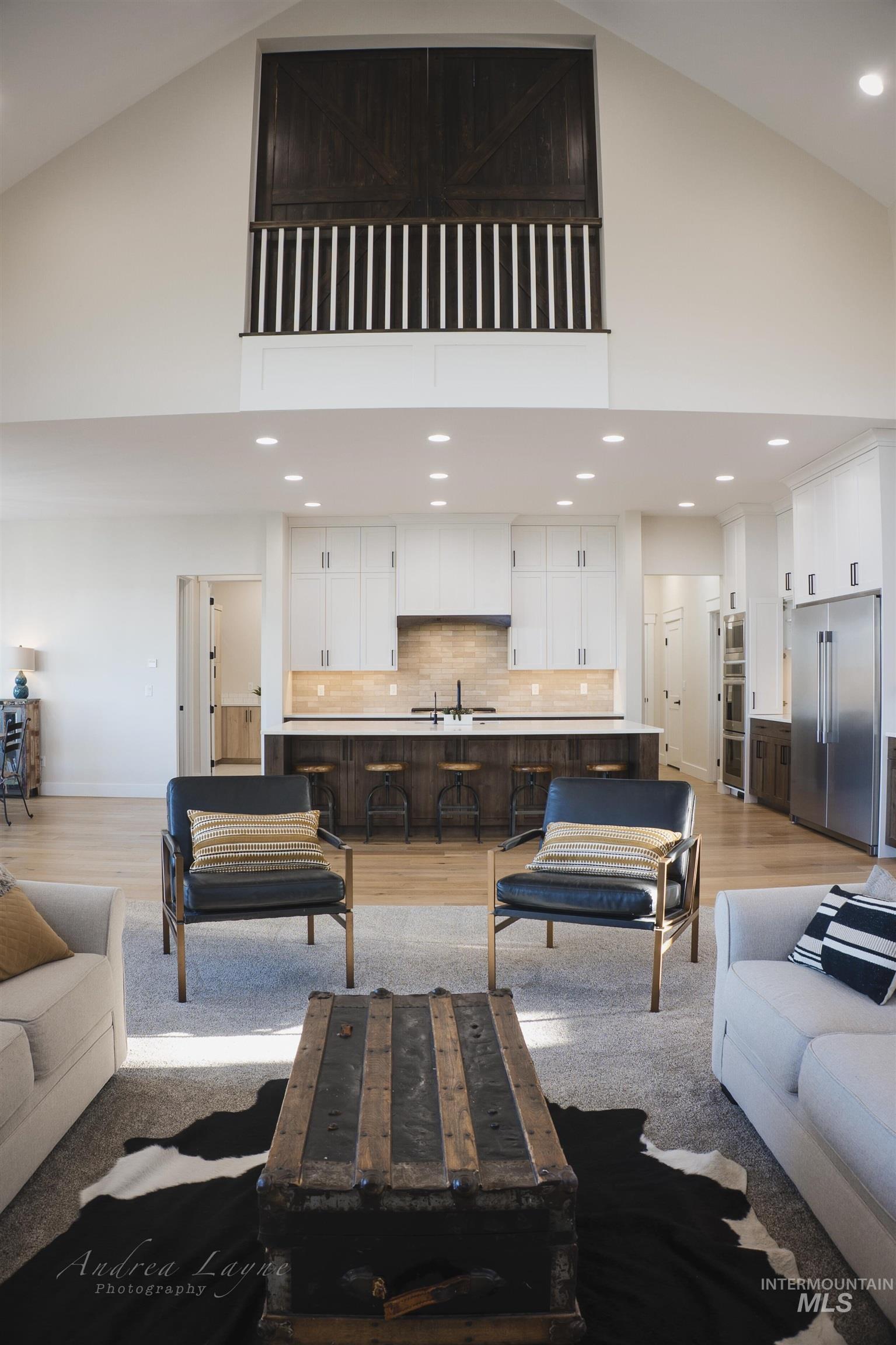 Living room with recessed lighting, high vaulted ceiling, and light wood-style floors