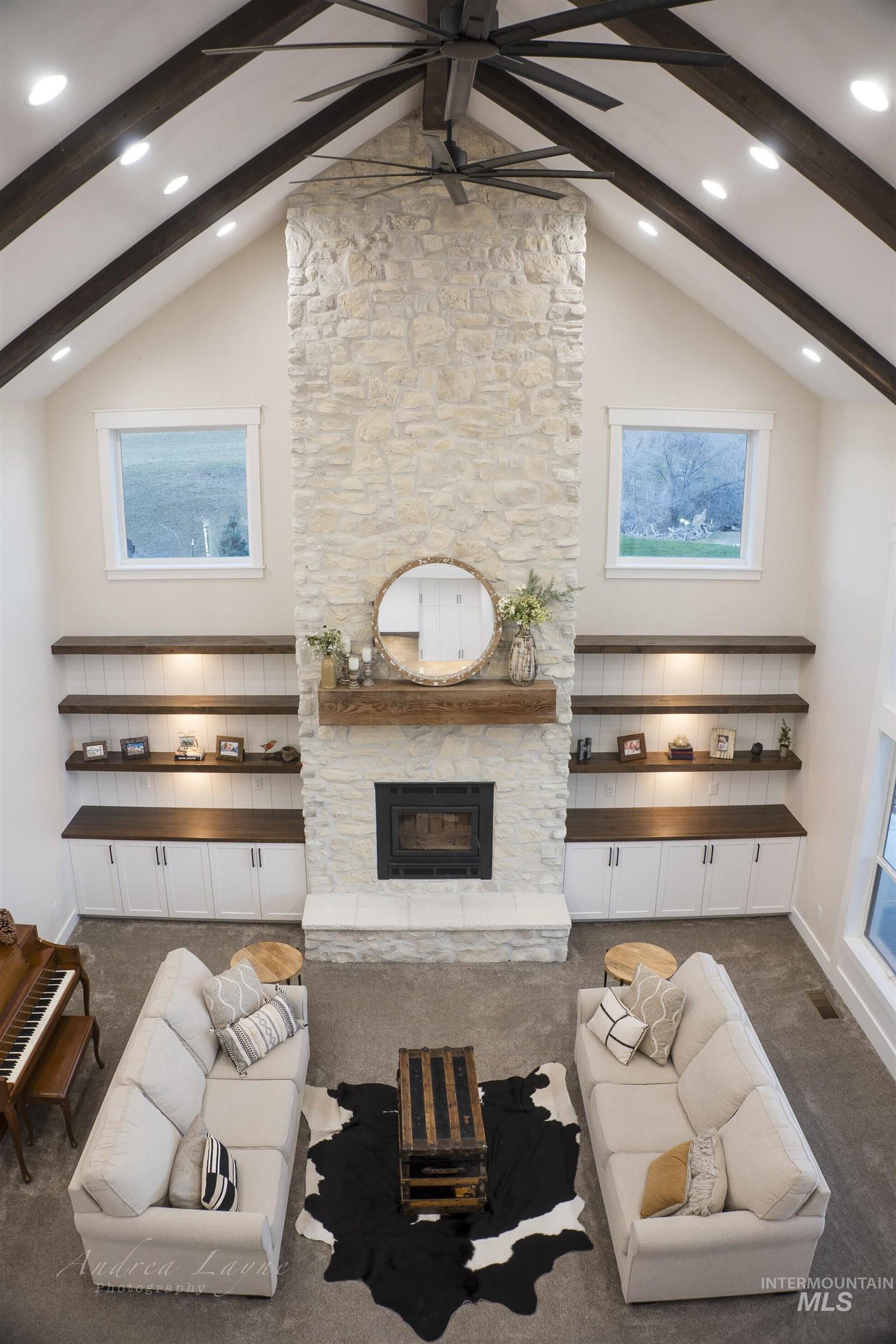 Living room with ceiling fan, high vaulted ceiling, beamed ceiling, carpet, and a fireplace