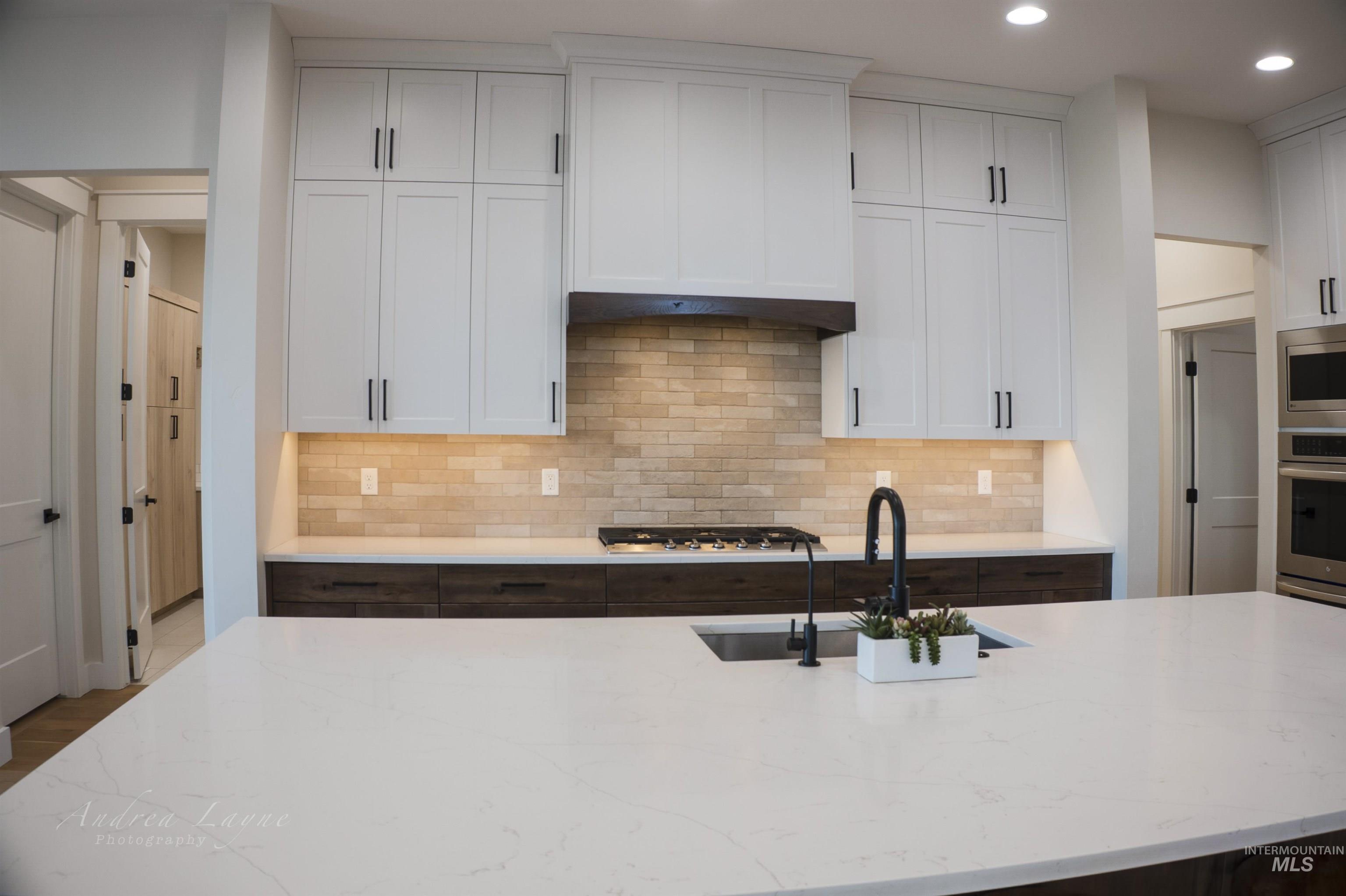 Kitchen with white cabinets, light stone countertops, decorative backsplash, and recessed lighting