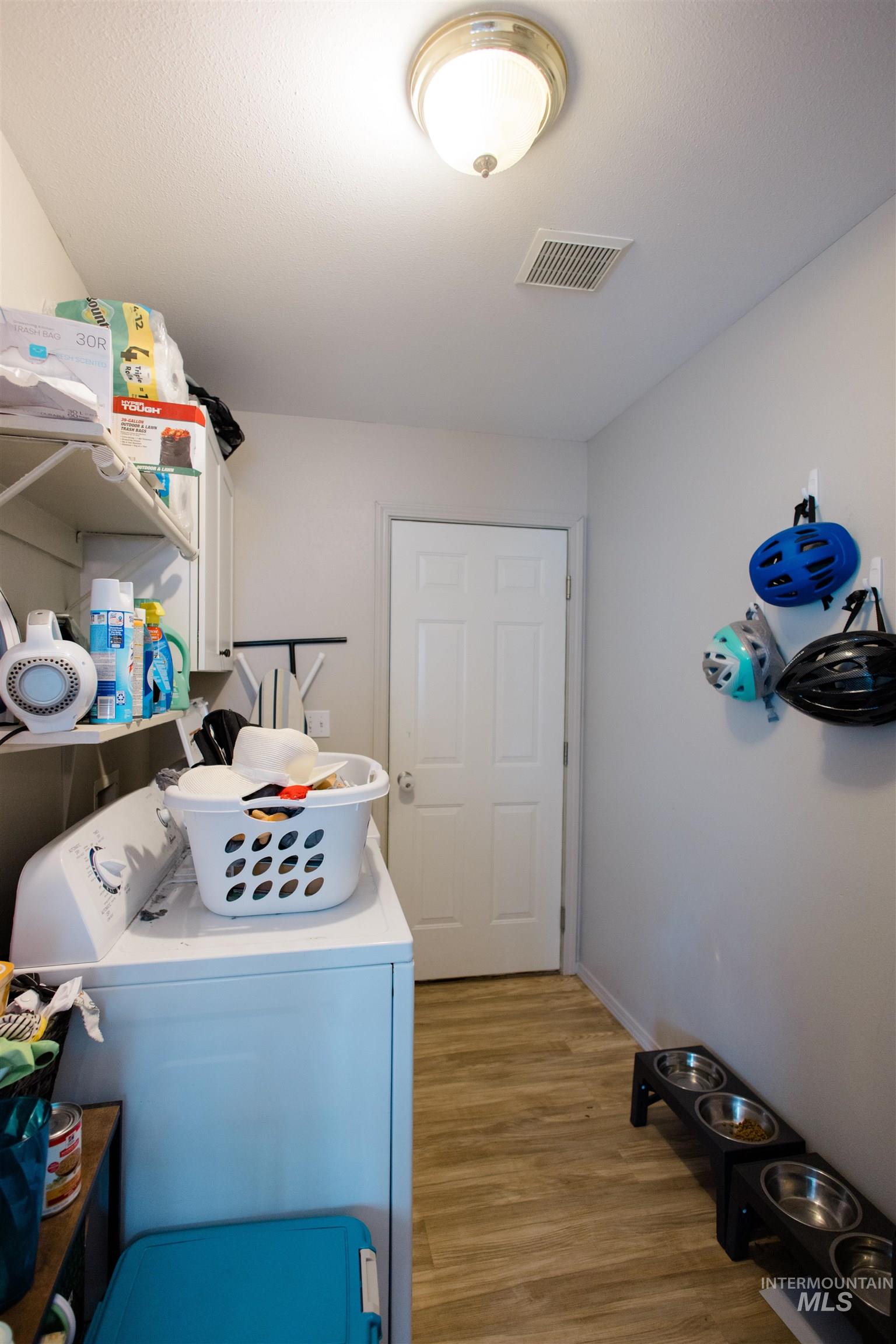 Laundry area featuring light wood-style flooring, cabinet space, and washing machine and clothes dryer