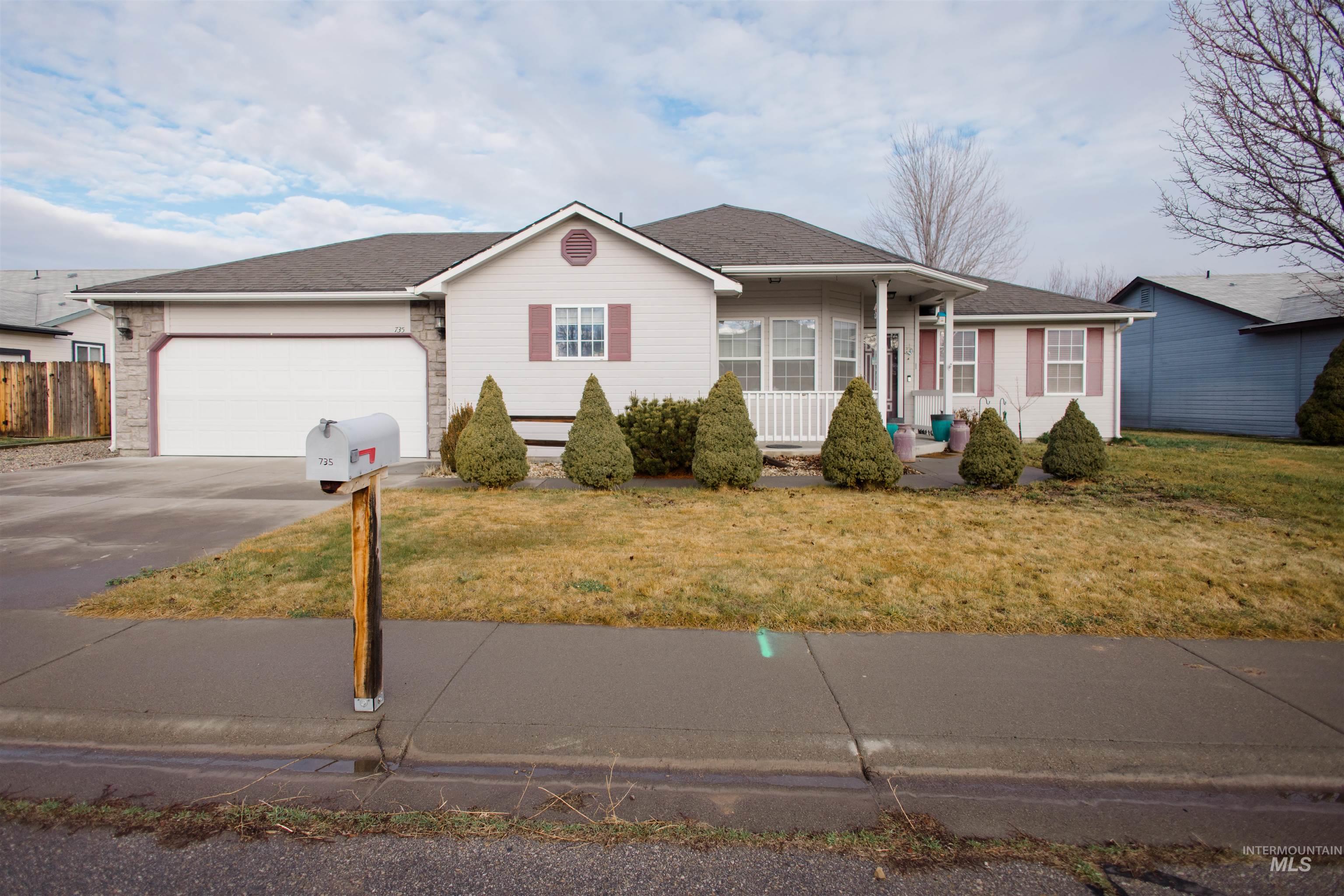 Ranch-style house with a porch, concrete driveway, a front lawn, roof with shingles, and a garage