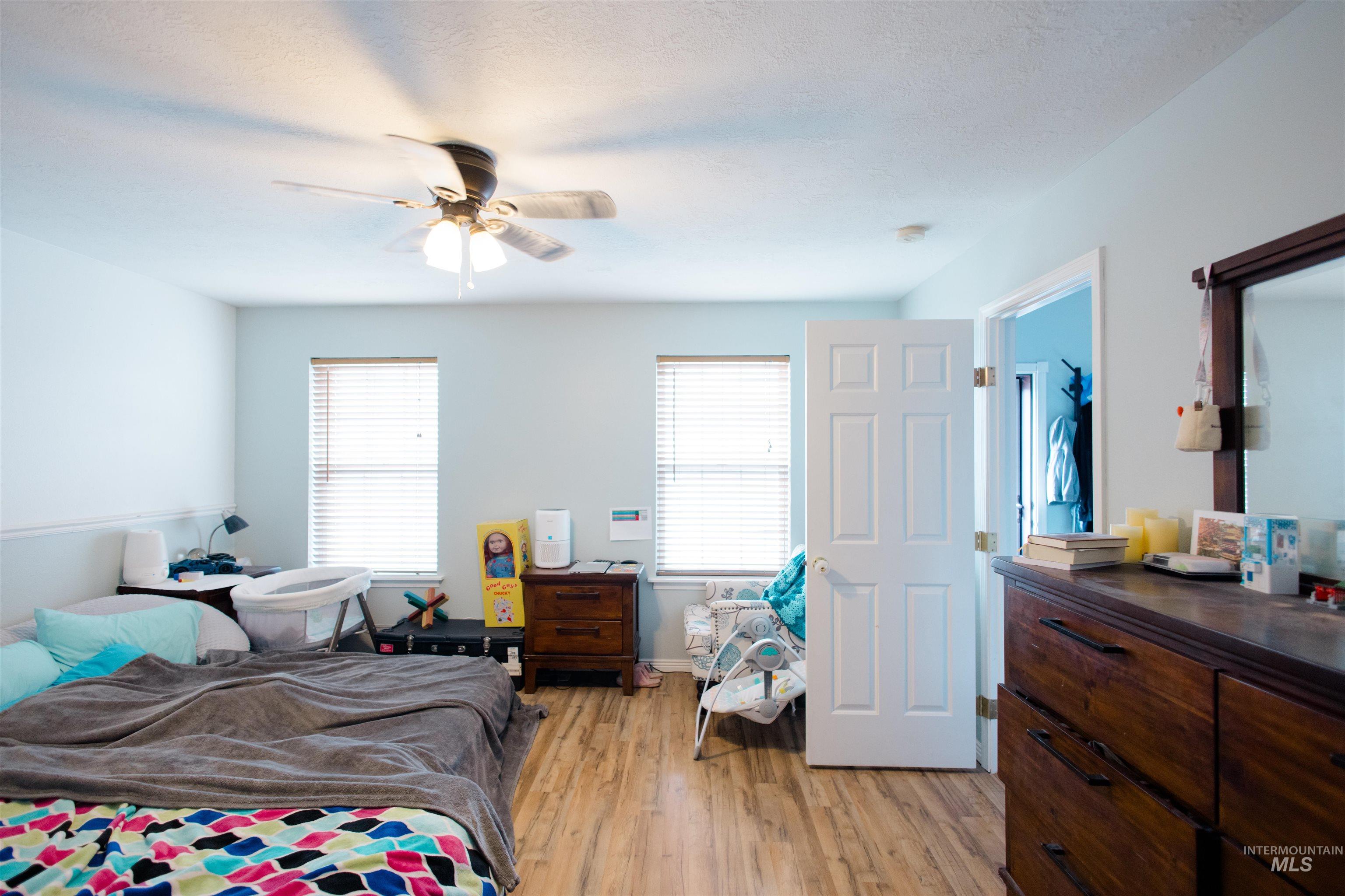 Bedroom featuring light wood finished floors, a ceiling fan, and a textured ceiling