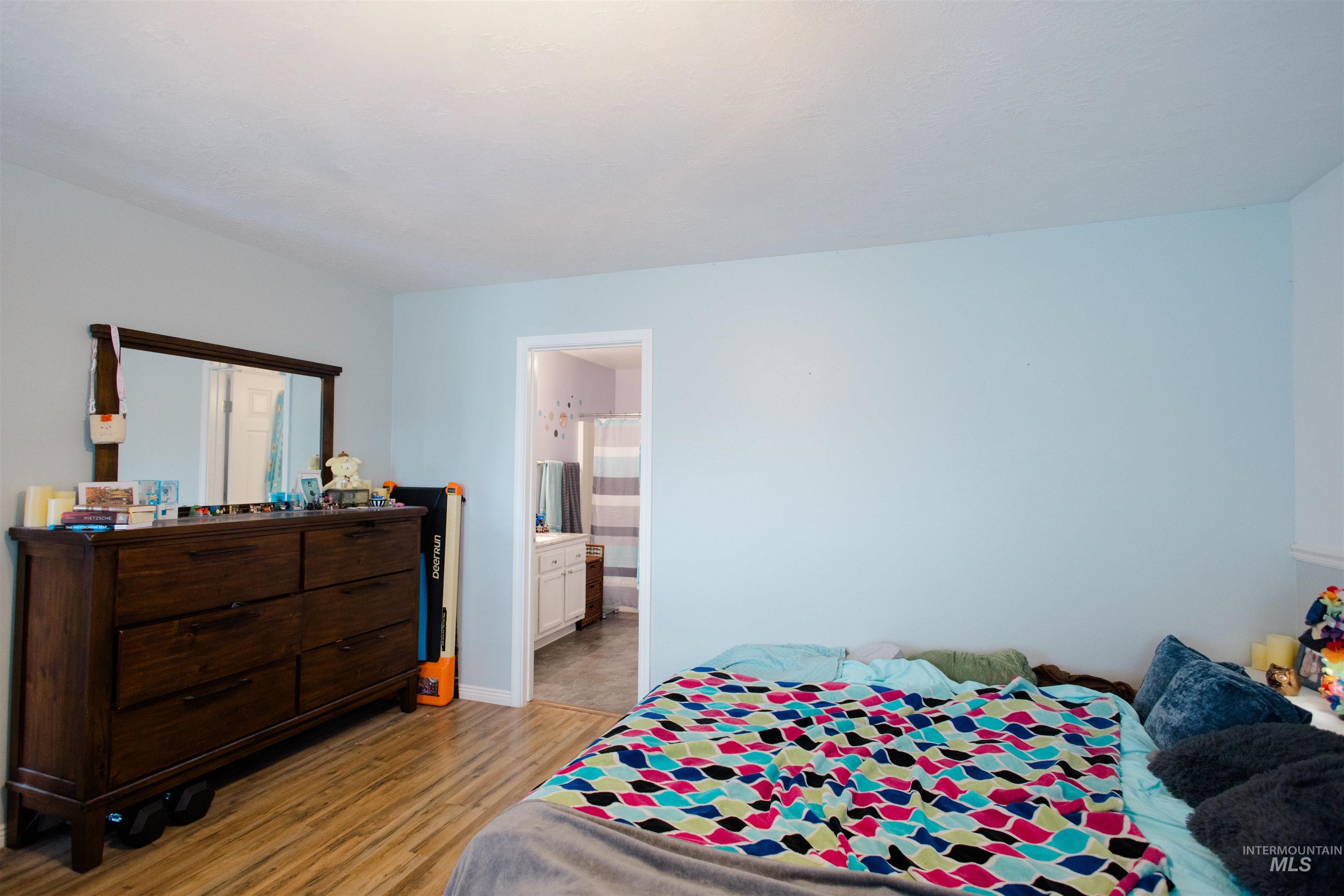 Bedroom with light wood-style floors and connected bathroom