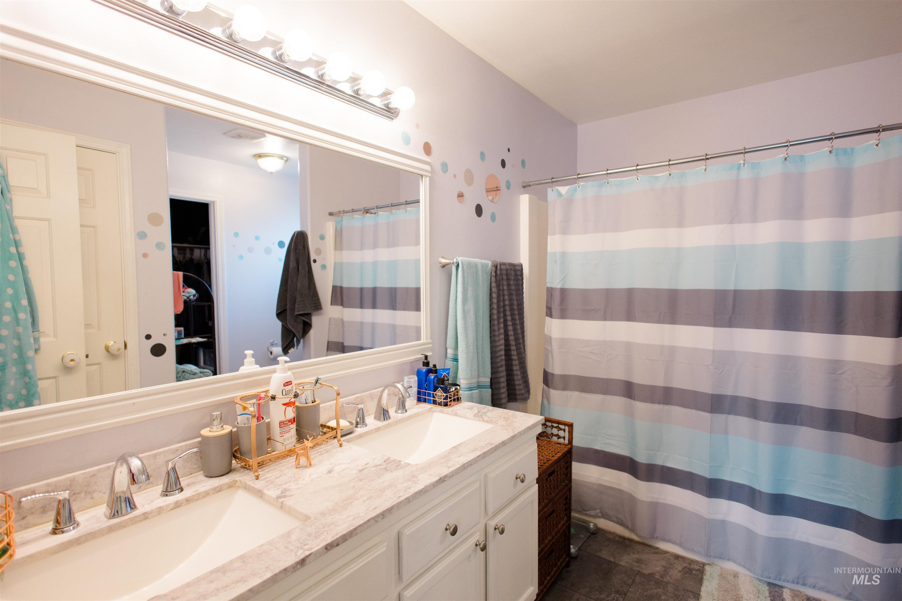 Full bathroom featuring double vanity, curtained shower, and a walk in closet