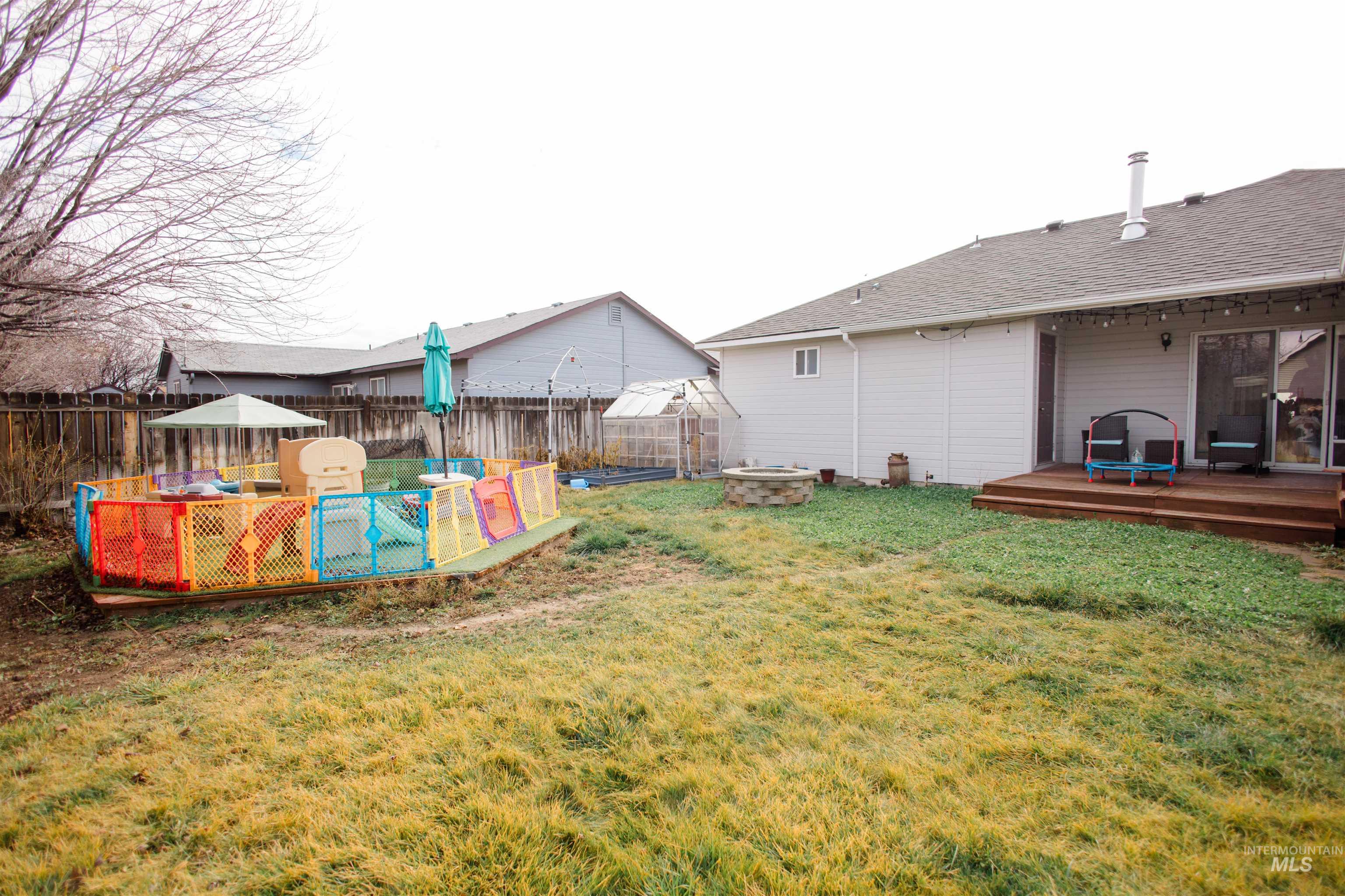 Fenced backyard with a wooden deck and an outdoor fire pit