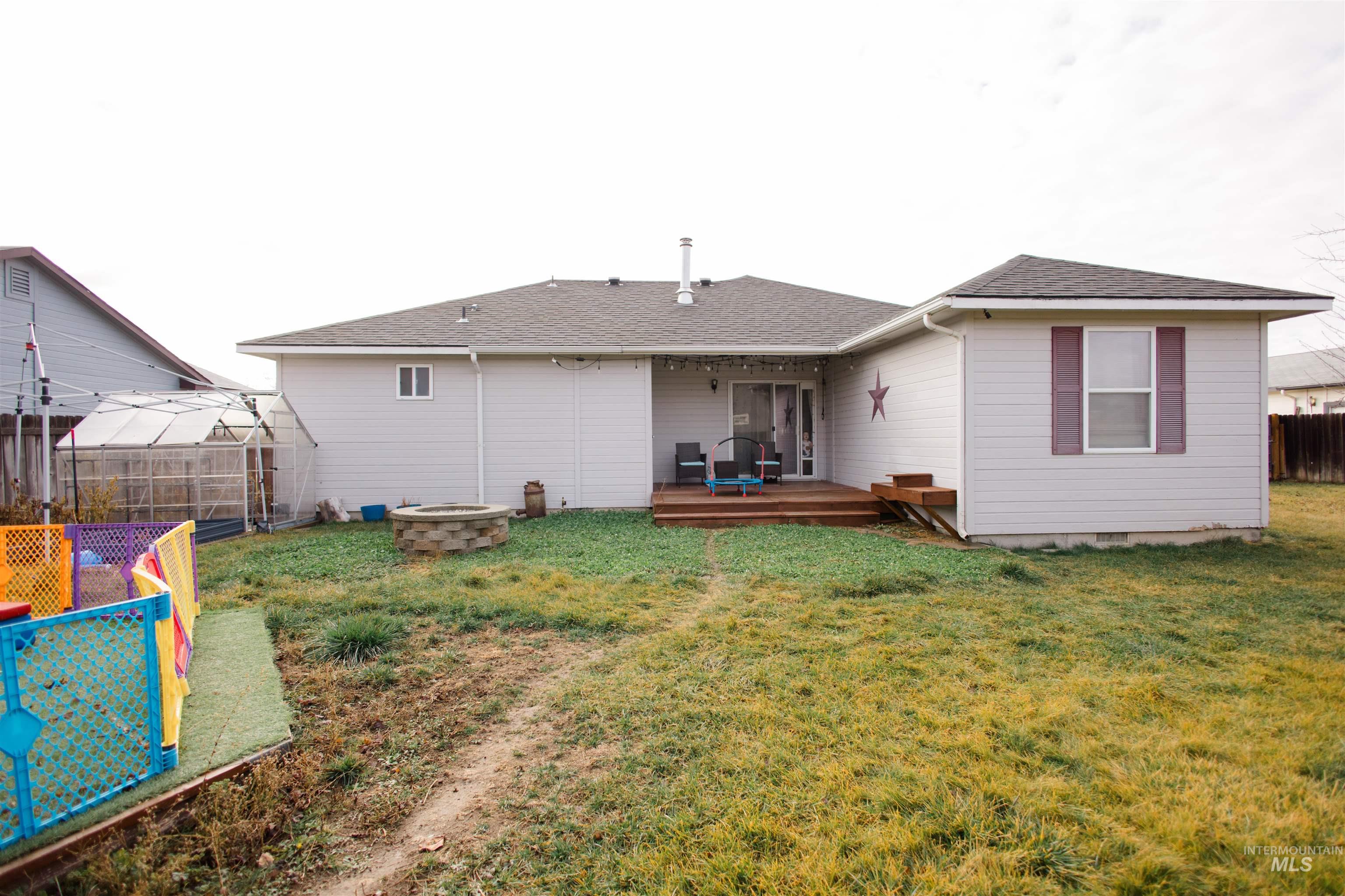 Back of property featuring a fenced backyard, a fire pit, roof with shingles, a deck, and crawl space