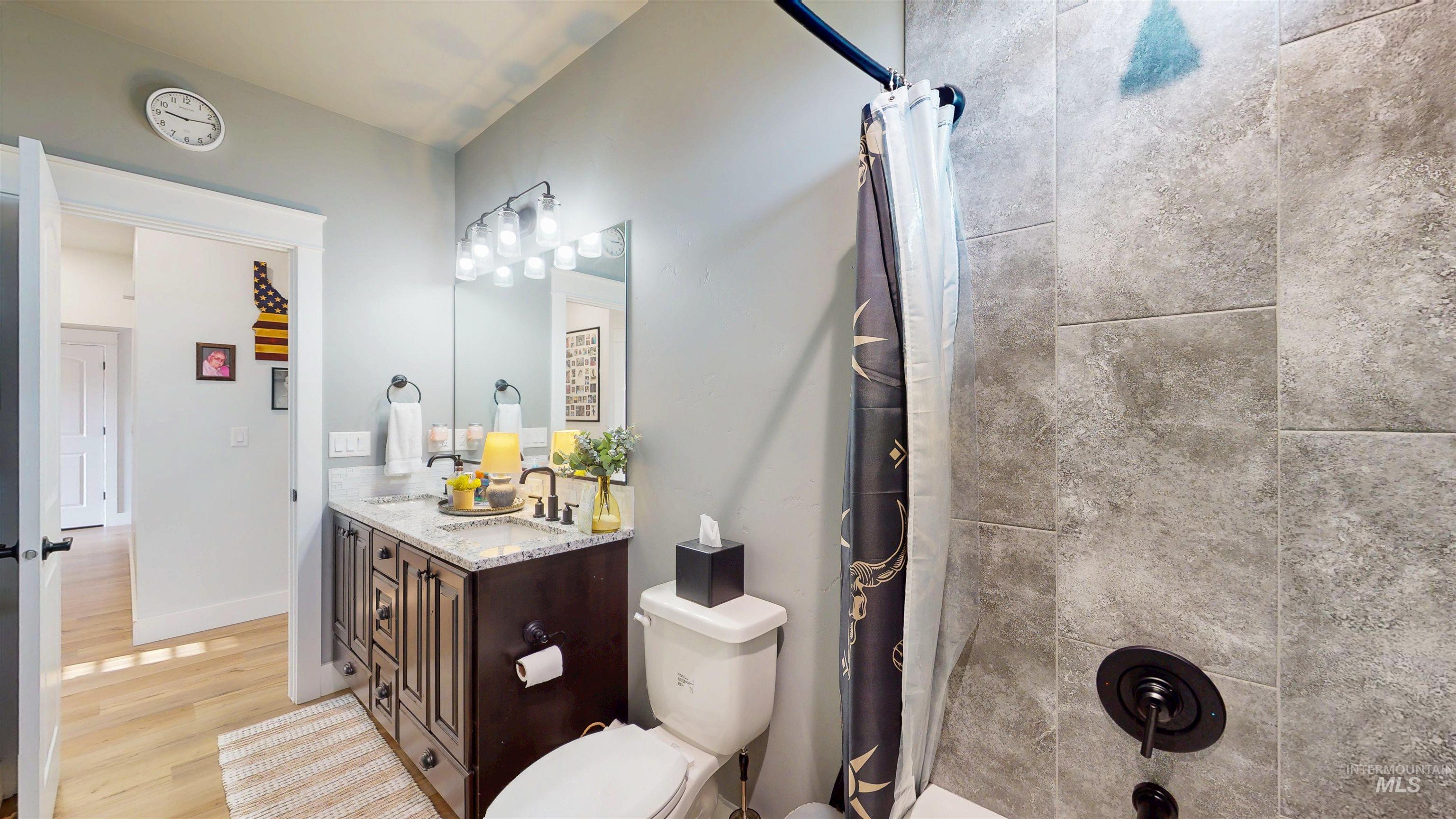 Full bathroom with vanity, light wood finished floors, and shower / bath combo with shower curtain