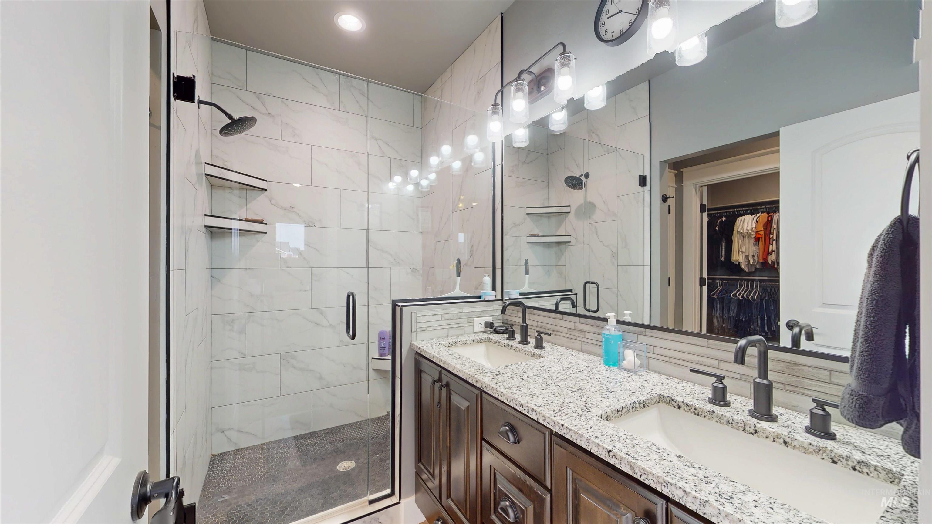 Full bath with a shower stall, a spacious closet, and double vanity