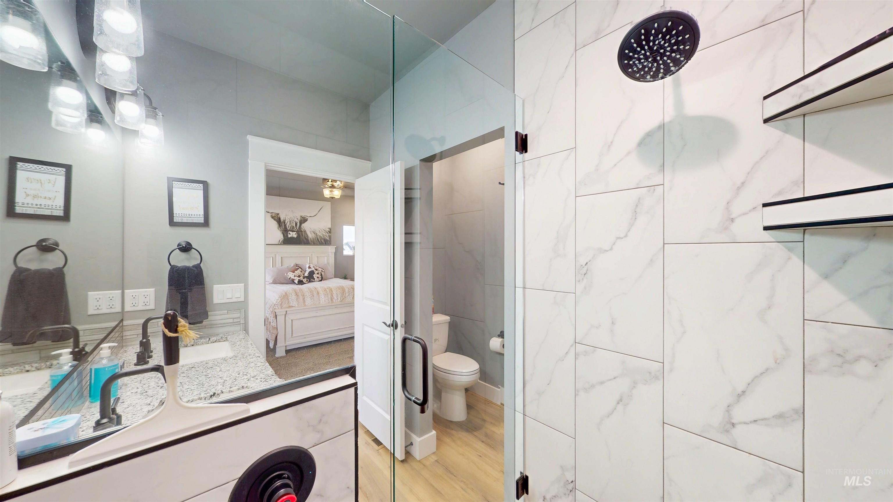 Bathroom with ensuite bathroom, vanity, walk in shower, and light wood-style flooring