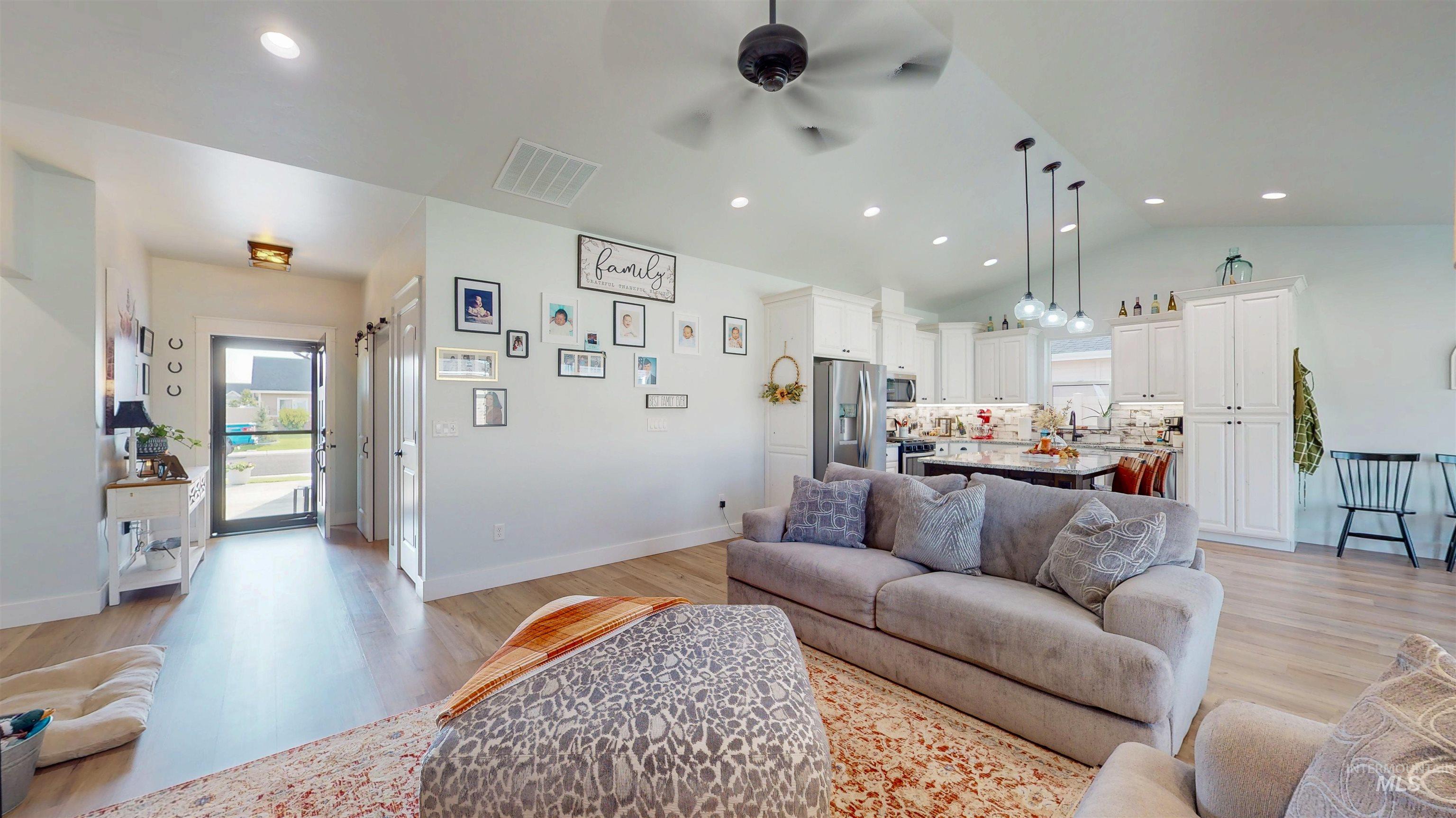 Living room featuring light wood-style flooring, recessed lighting, ceiling fan, and vaulted ceiling
