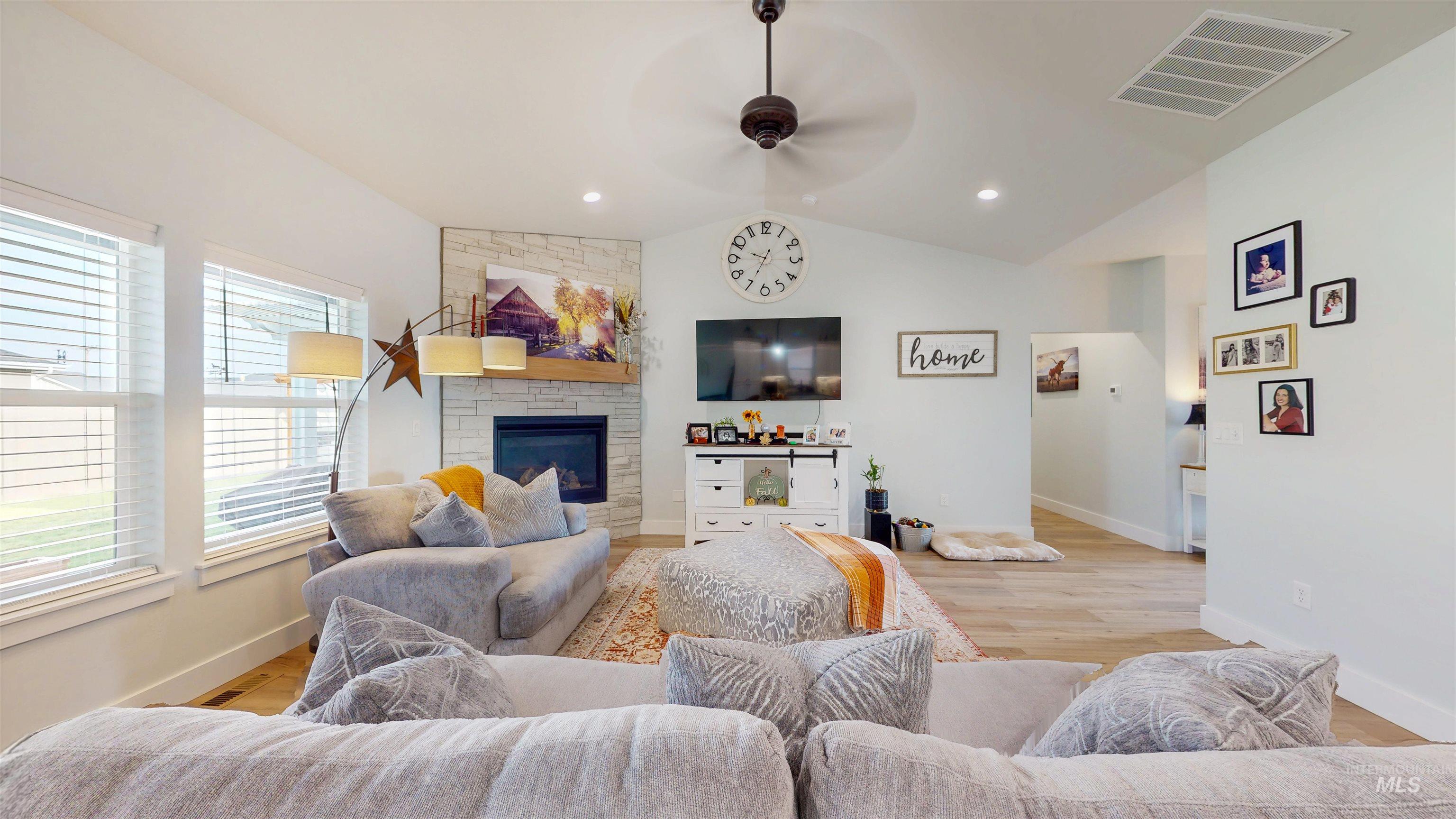 Living area featuring vaulted ceiling, ceiling fan, light wood finished floors, a fireplace, and recessed lighting