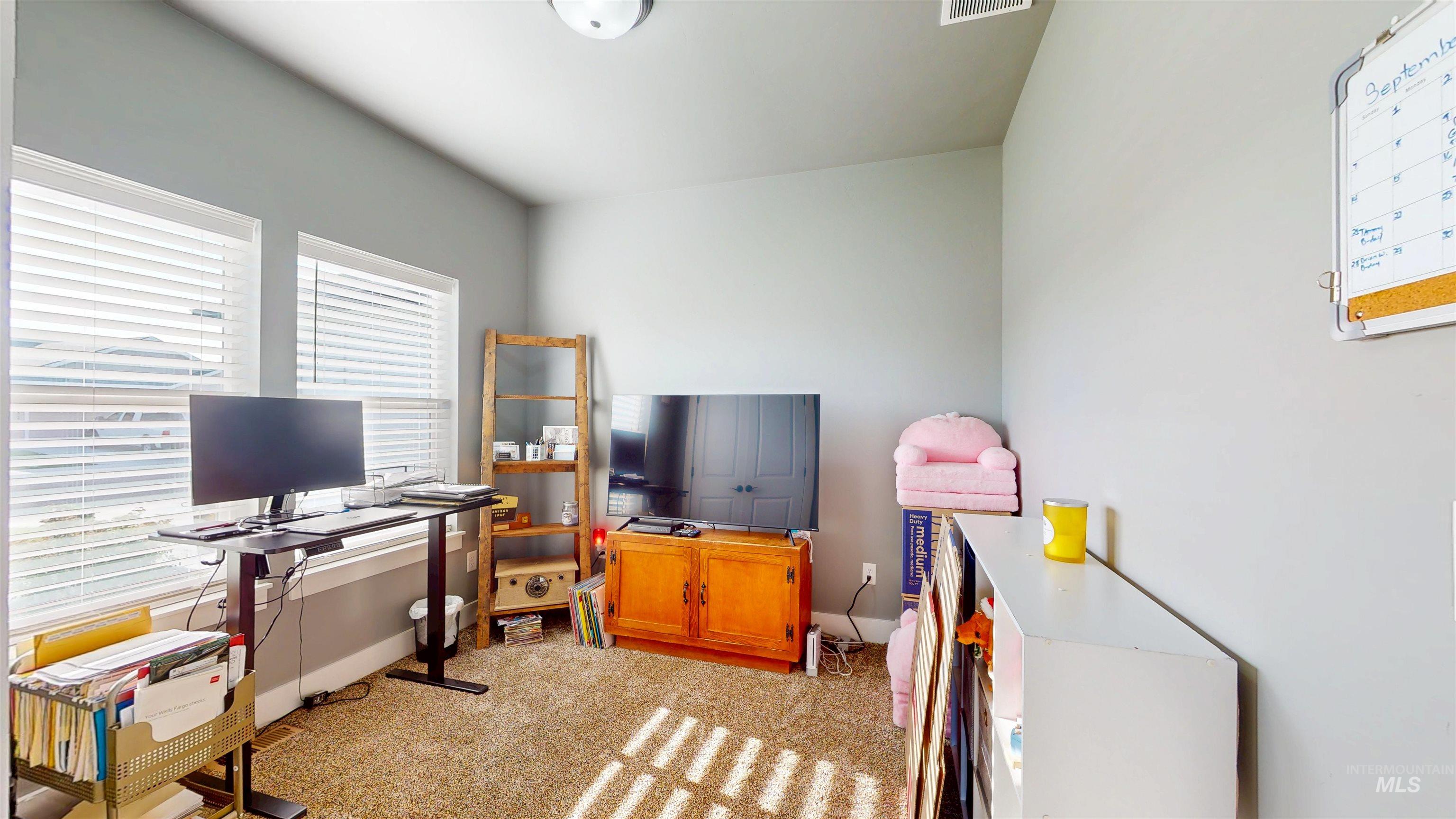 Office space featuring plenty of natural light and light colored carpet
