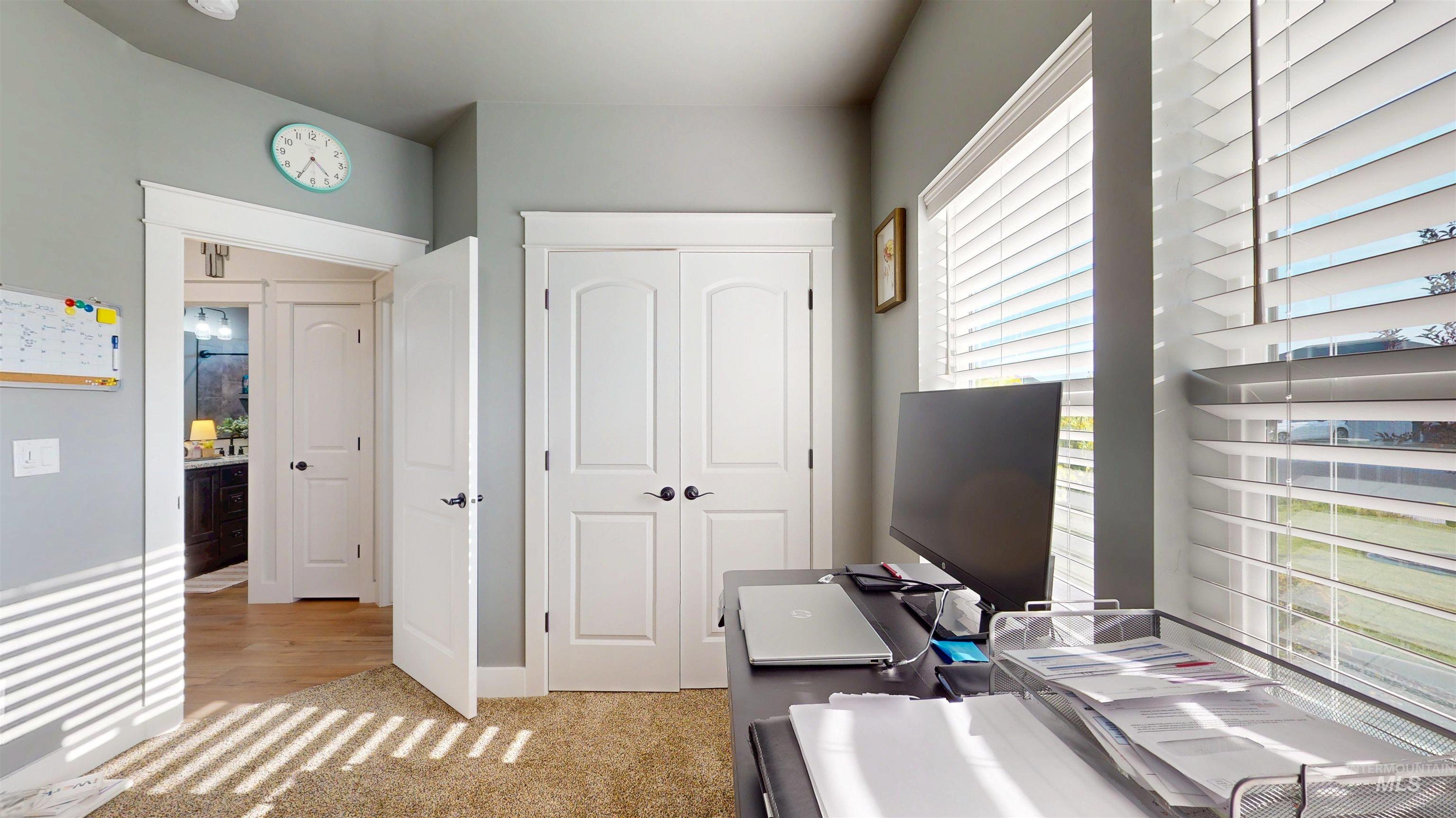 Office area featuring light colored carpet and baseboards