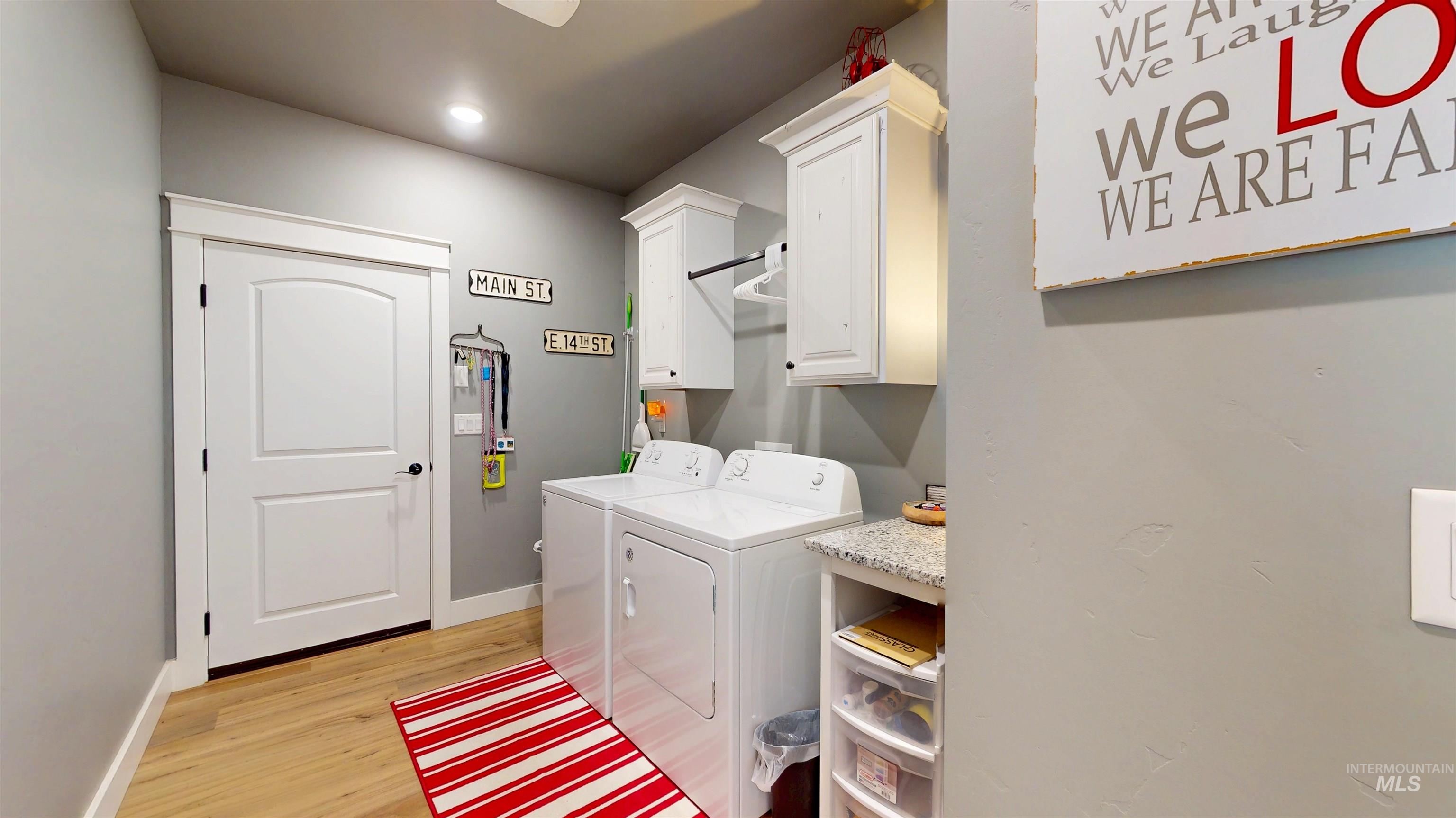 Laundry area with light wood-style floors, cabinet space, and washing machine and clothes dryer