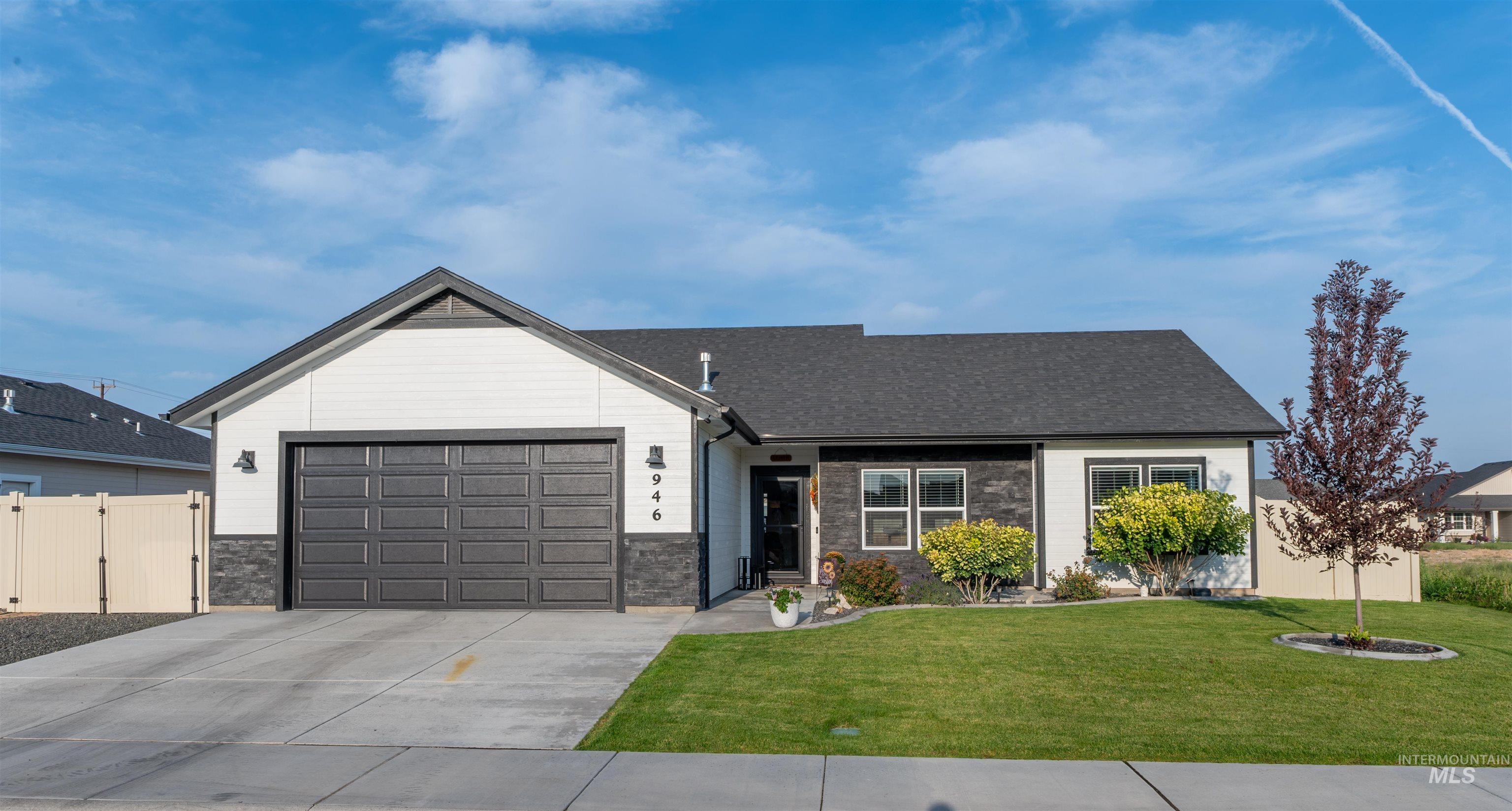 View of front of property with stone siding, driveway, an attached garage, and a shingled roof