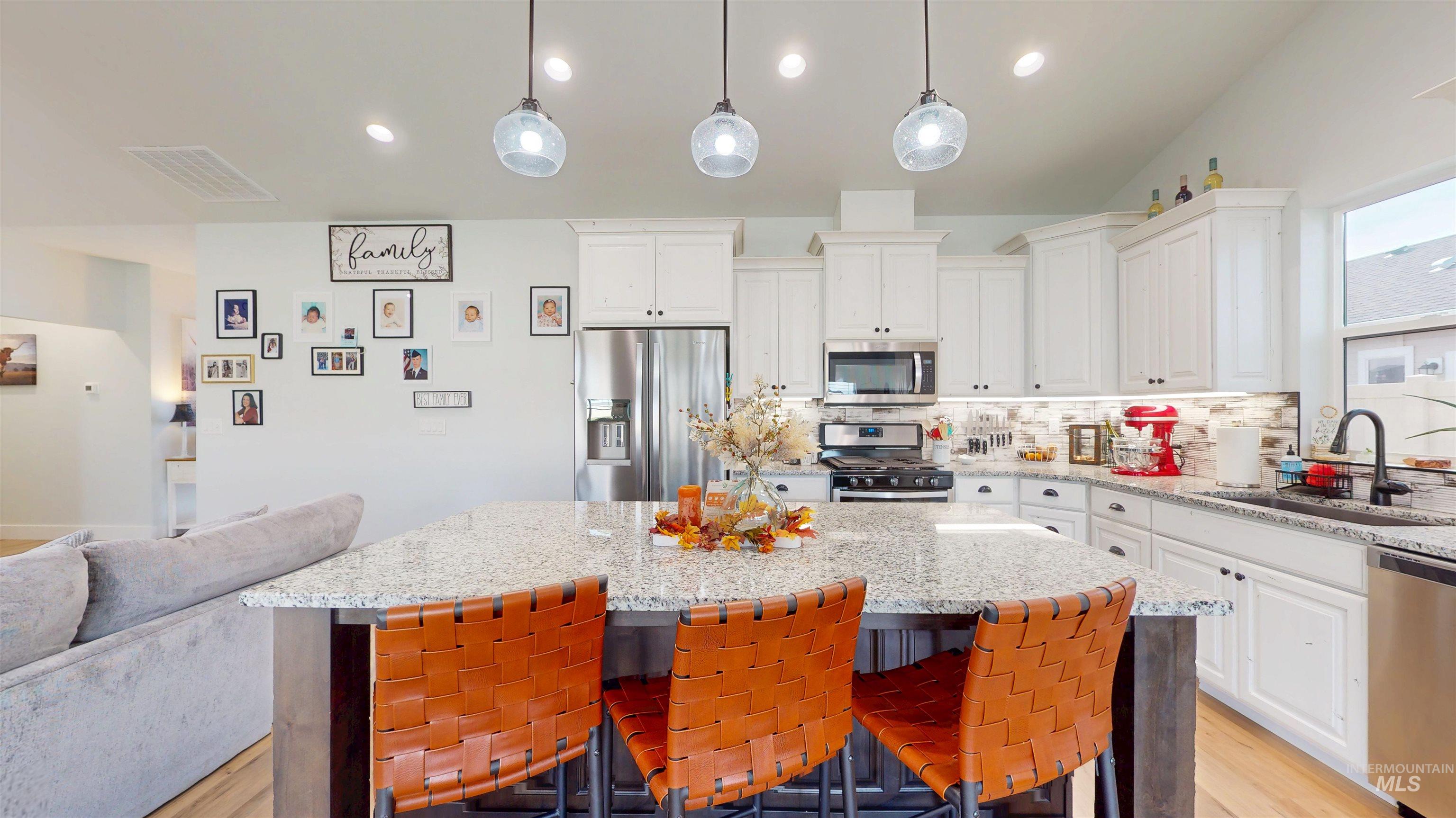 Kitchen with decorative backsplash, stainless steel appliances, light wood-style floors, light stone counters, and recessed lighting