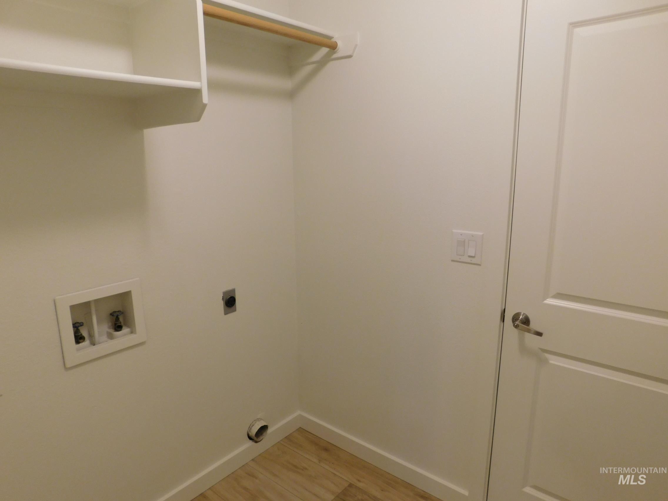Washroom featuring light wood-type flooring, hookup for a washing machine, and hookup for an electric dryer