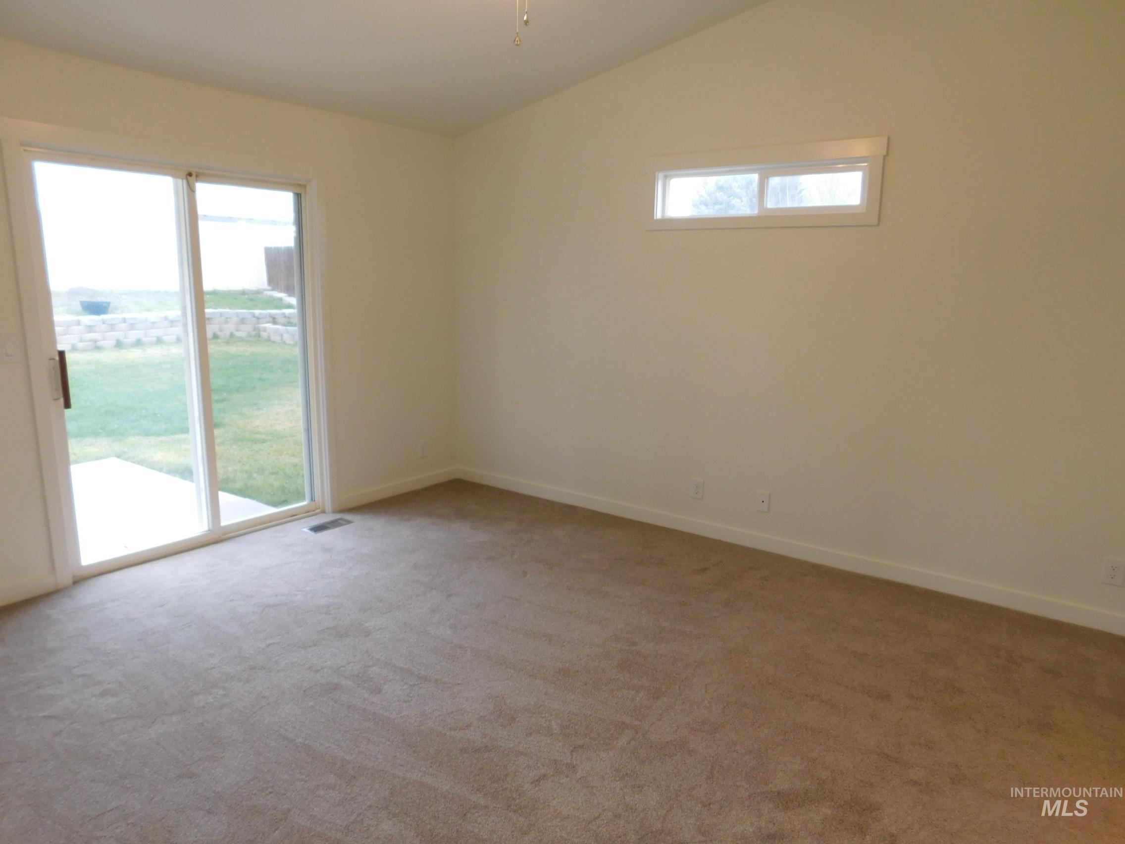 Empty room featuring lofted ceiling and light colored carpet