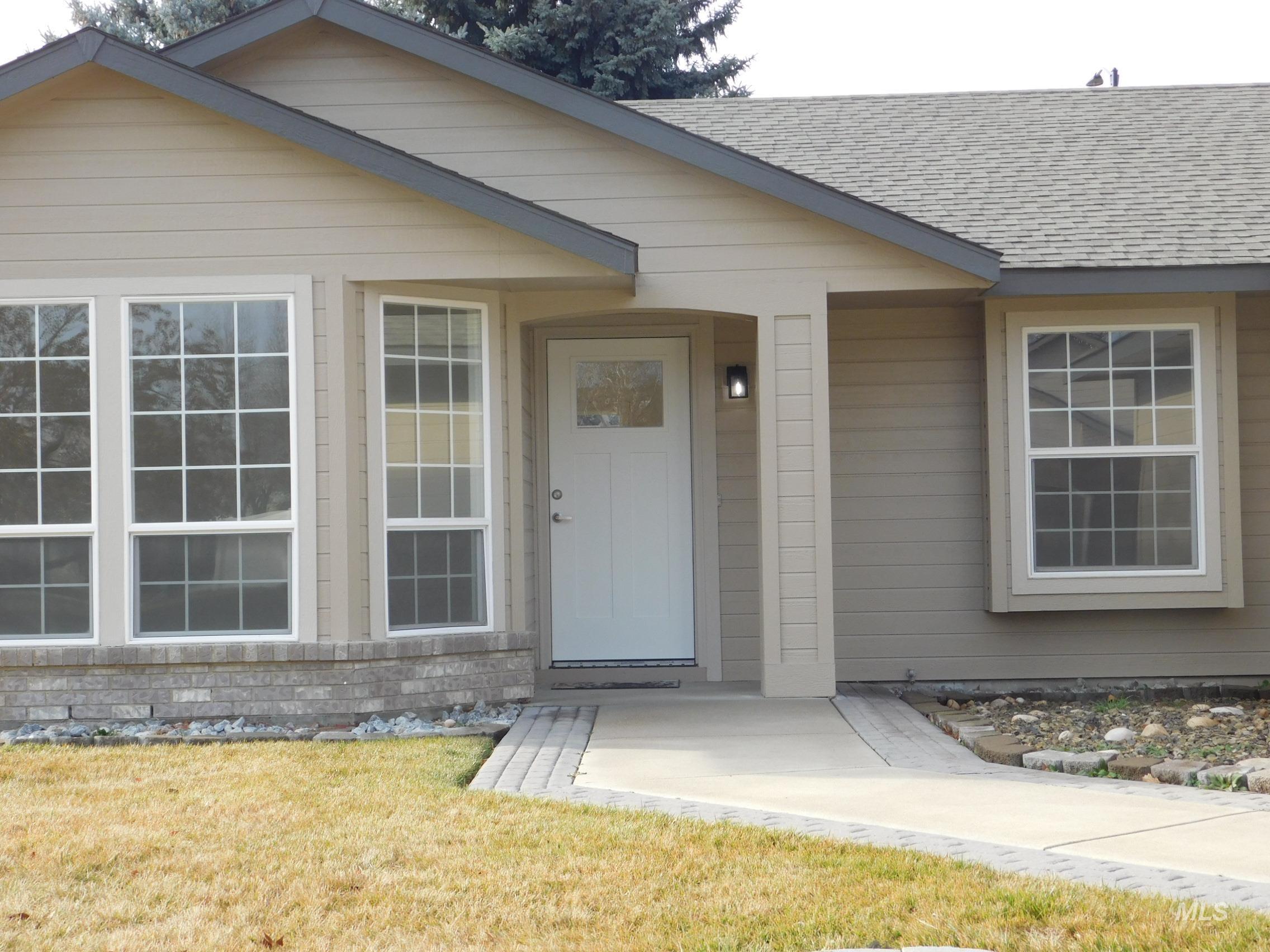 View of exterior entry with a shingled roof and a yard