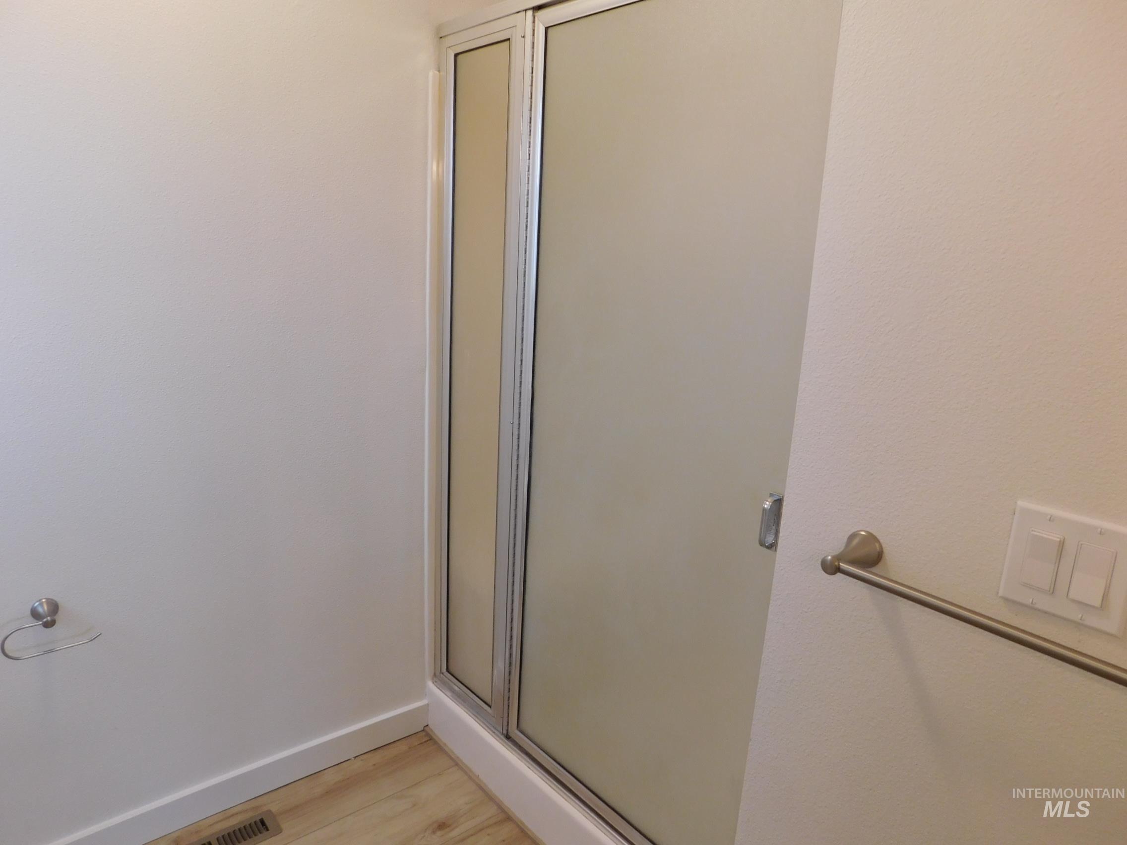 Full bathroom featuring a stall shower and light wood finished floors