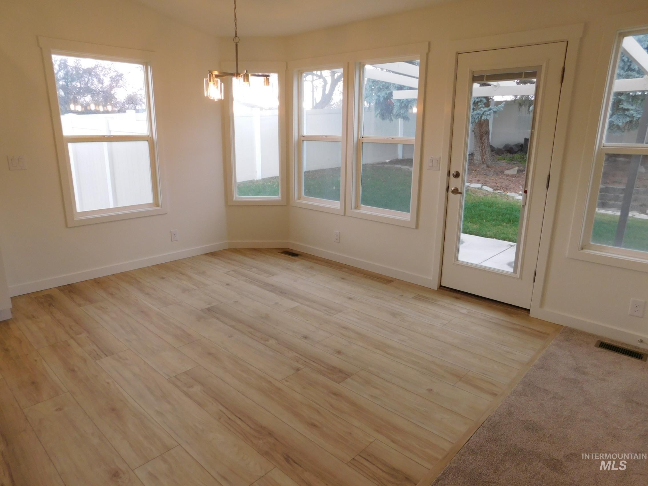 Unfurnished dining area with light wood finished floors, a chandelier, and plenty of natural light