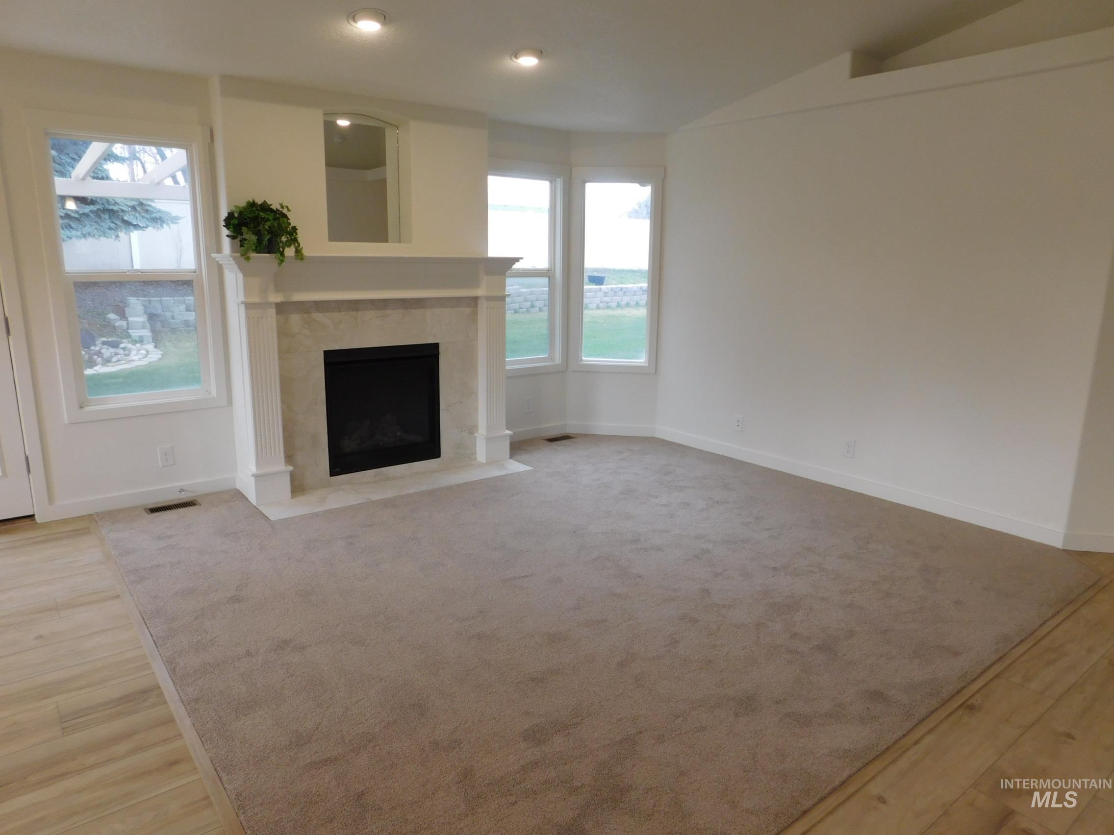 Unfurnished living room featuring a fireplace, light wood-type flooring, recessed lighting, and lofted ceiling