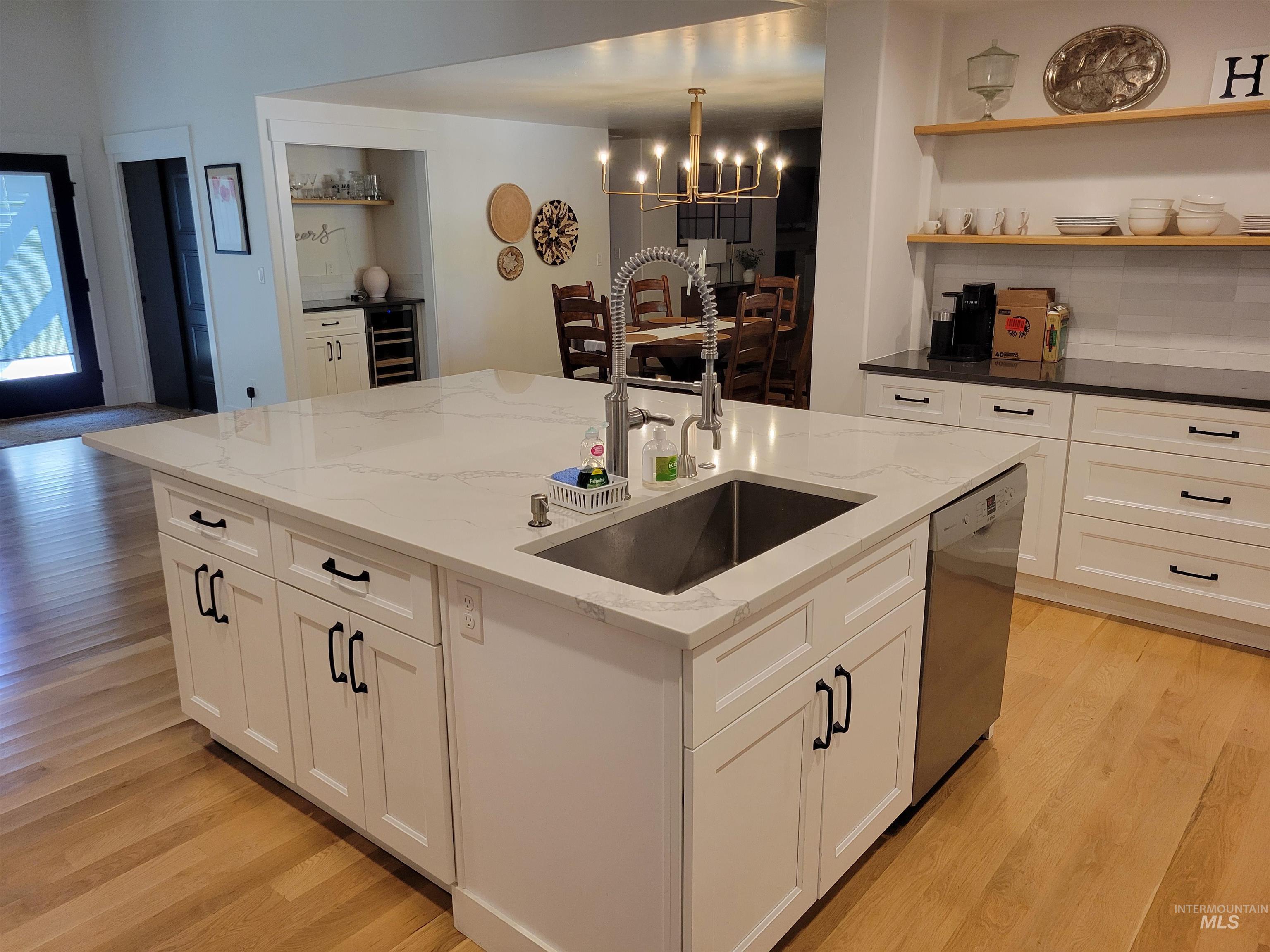 Kitchen featuring light wood-type flooring, a chandelier, and an island with sink