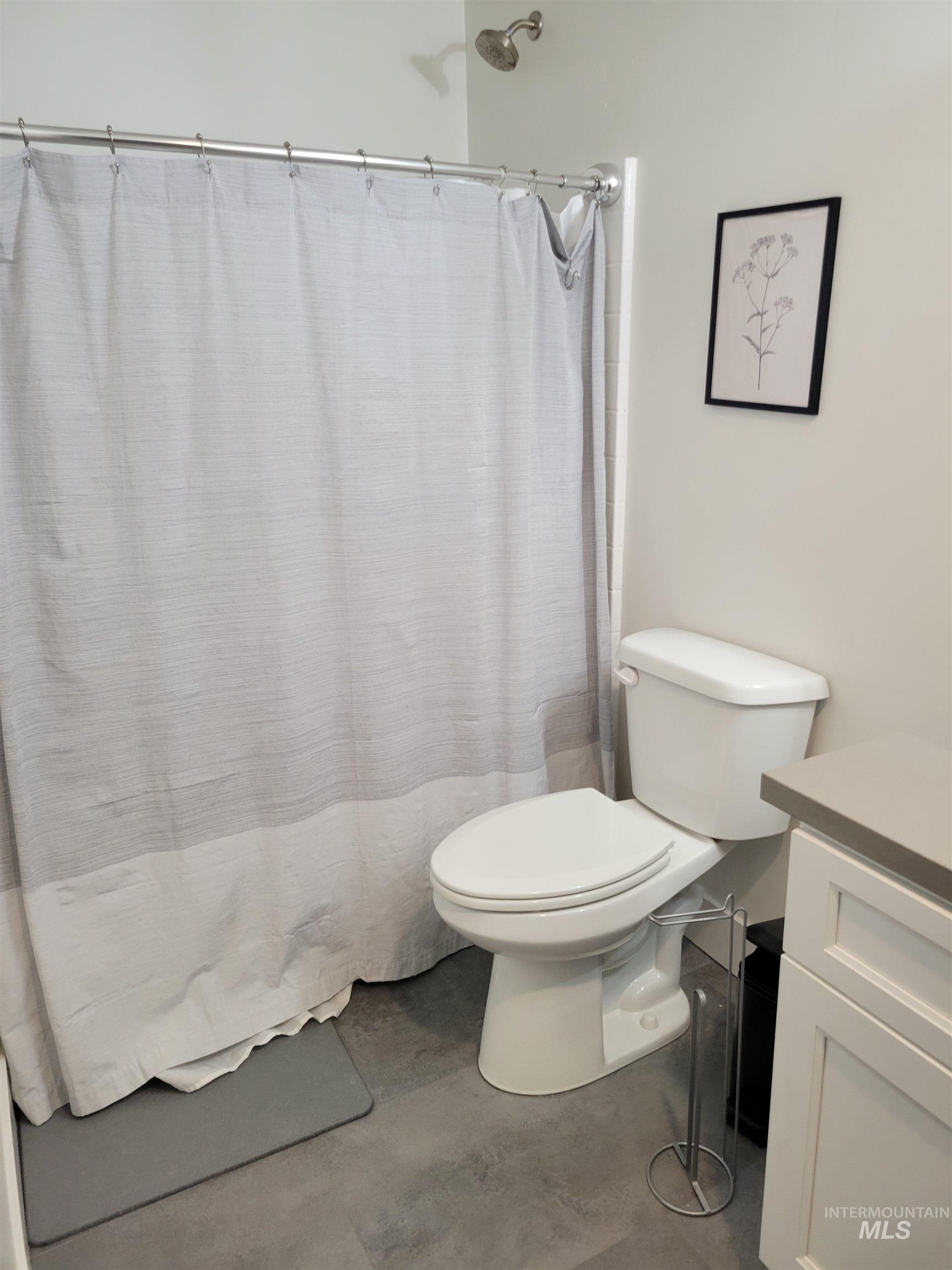 Bathroom with finished concrete flooring, vanity, and a shower with shower curtain