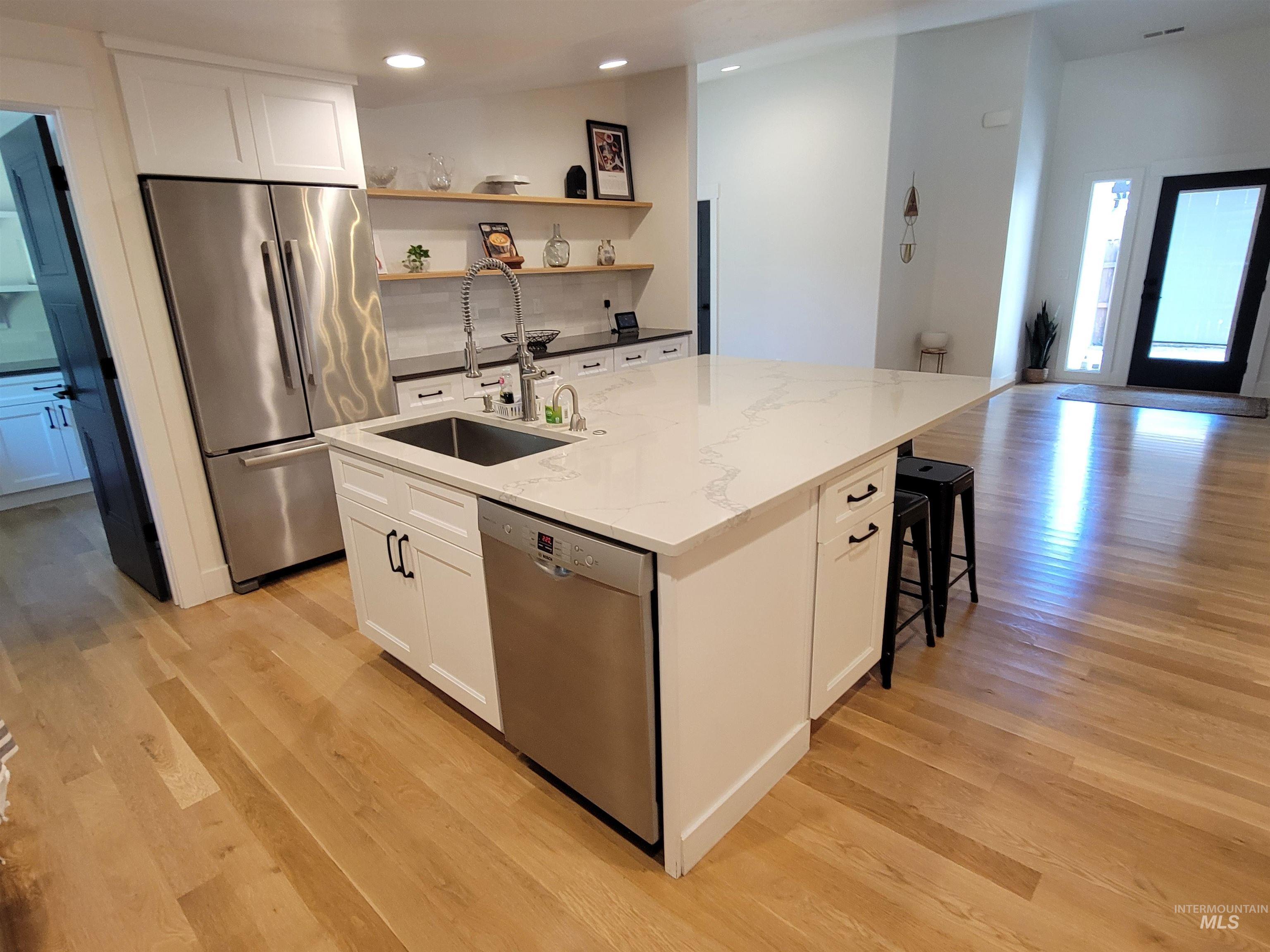 Kitchen featuring appliances with stainless steel finishes, light wood-type flooring, white cabinetry, open shelves, and recessed lighting