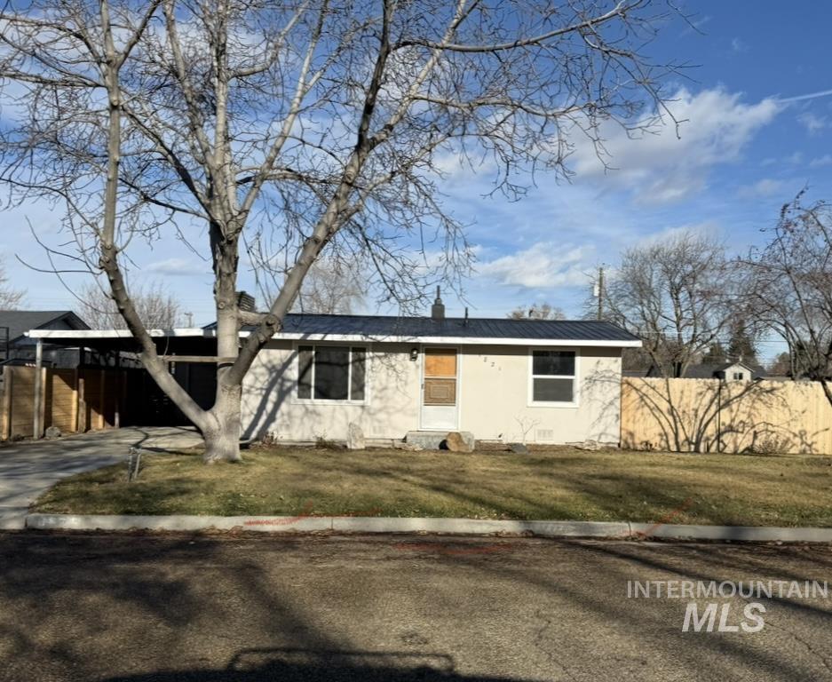 View of front facade with a metal roof, an attached carport, driveway, and a chimney