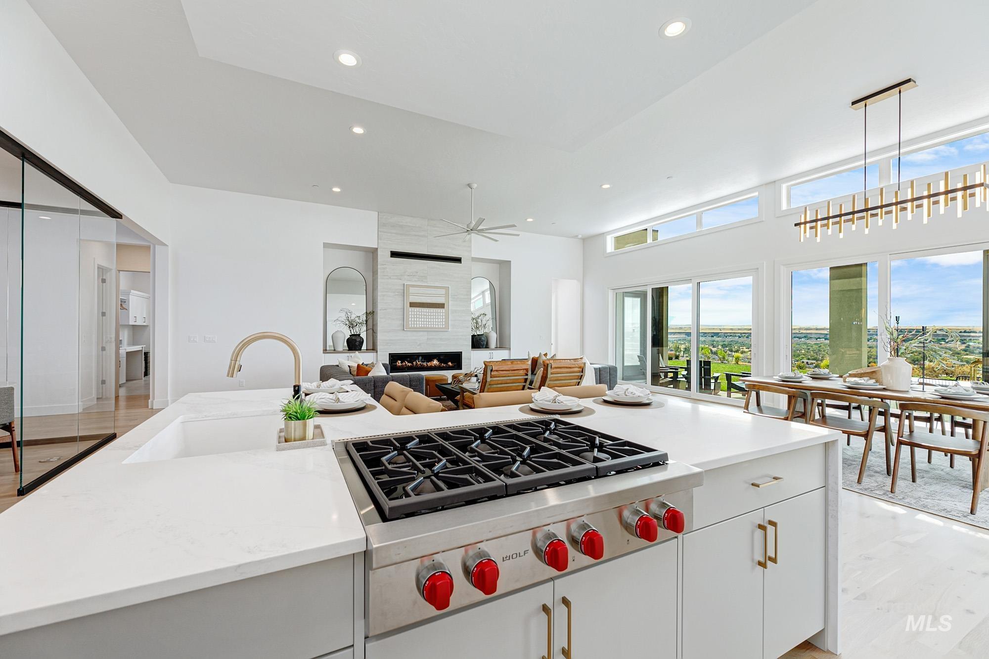 Kitchen with white cabinets, stainless steel gas stovetop, light wood-style floors, a fireplace, and a ceiling fan