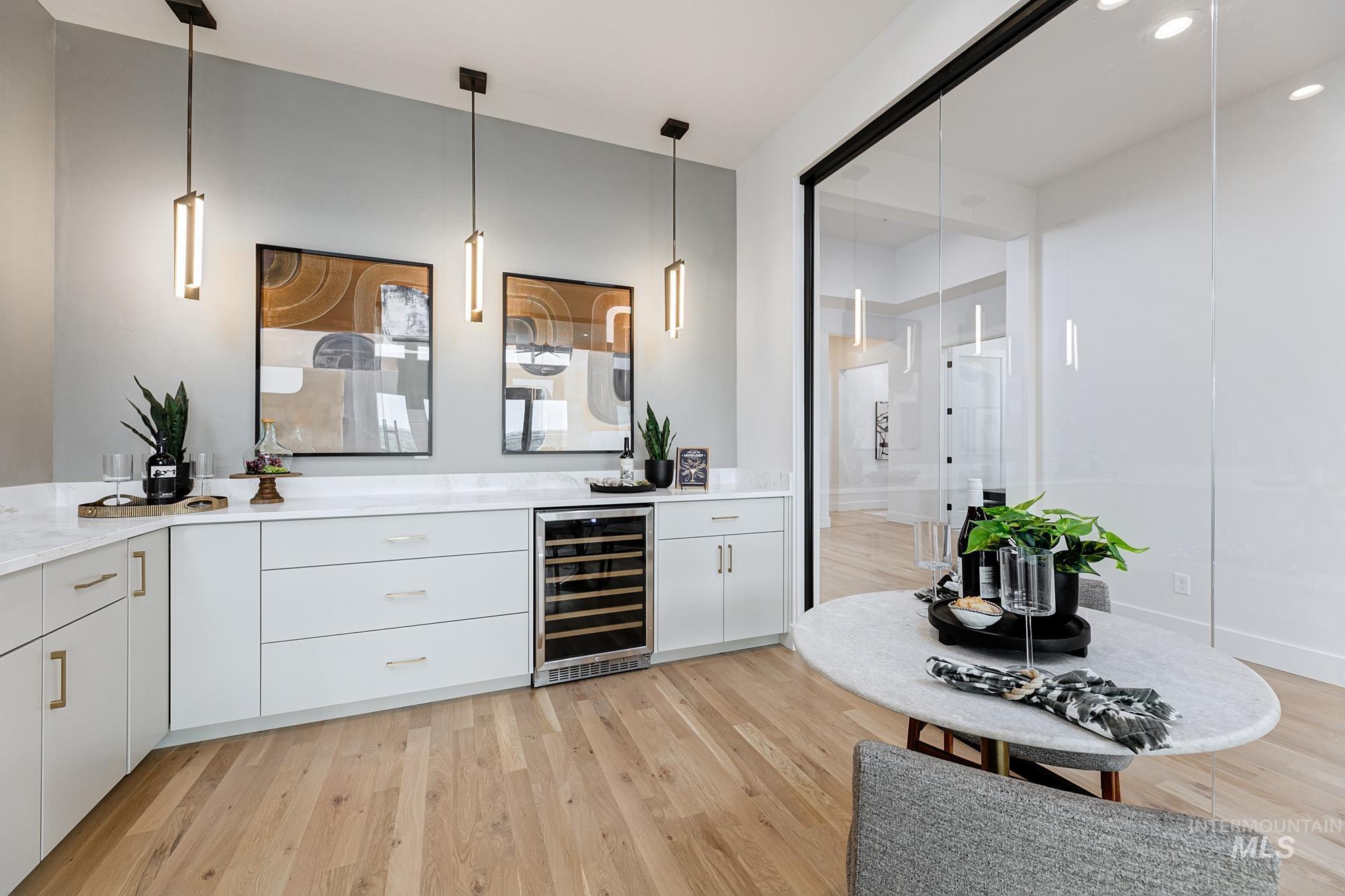 Bar area featuring light wood-type flooring, wine cooler, white cabinetry, pendant lighting, and recessed lighting