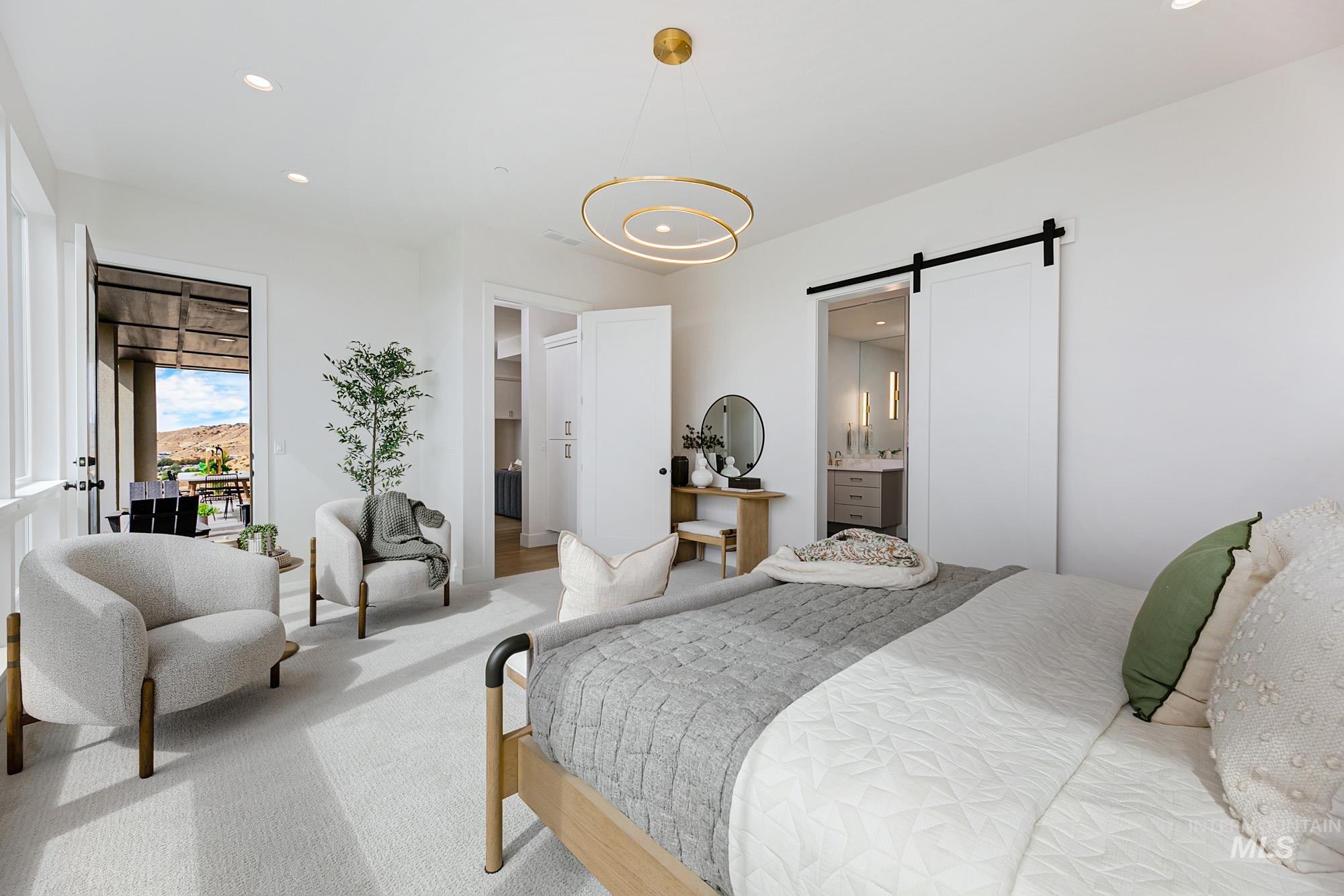 Carpeted bedroom with a barn door, recessed lighting, ensuite bathroom, and access to exterior