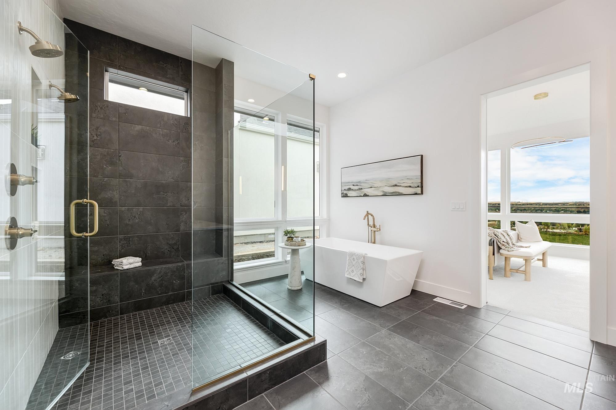 Bathroom featuring a freestanding tub, a stall shower, and dark tile patterned floors