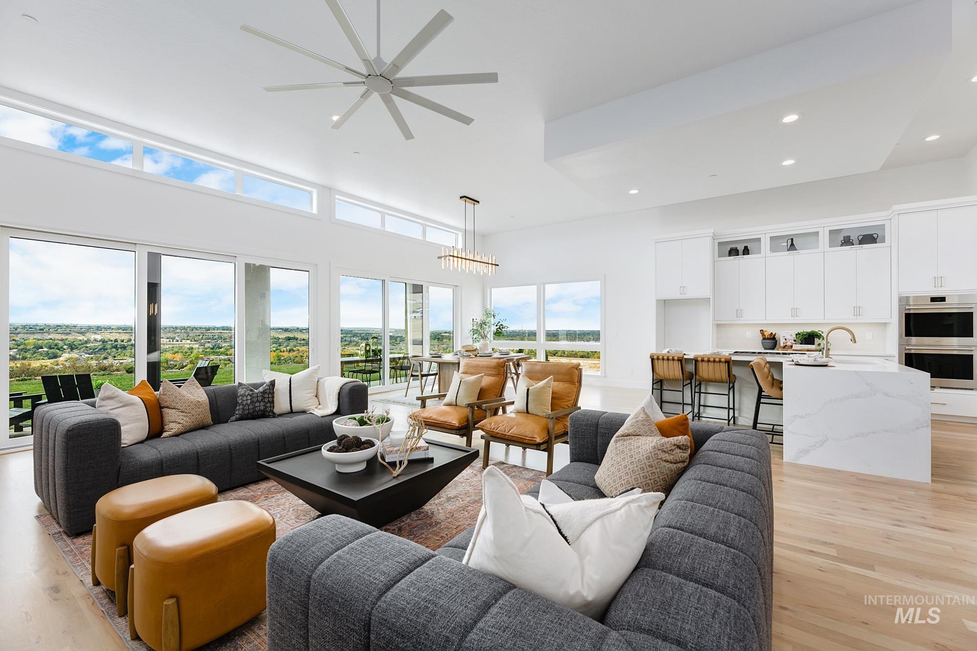 Living area featuring light wood-style flooring, recessed lighting, and a towering ceiling