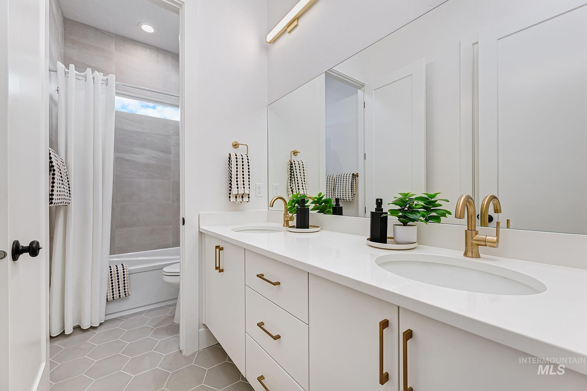 Full bathroom featuring double vanity, shower / tub combo, and light tile patterned flooring